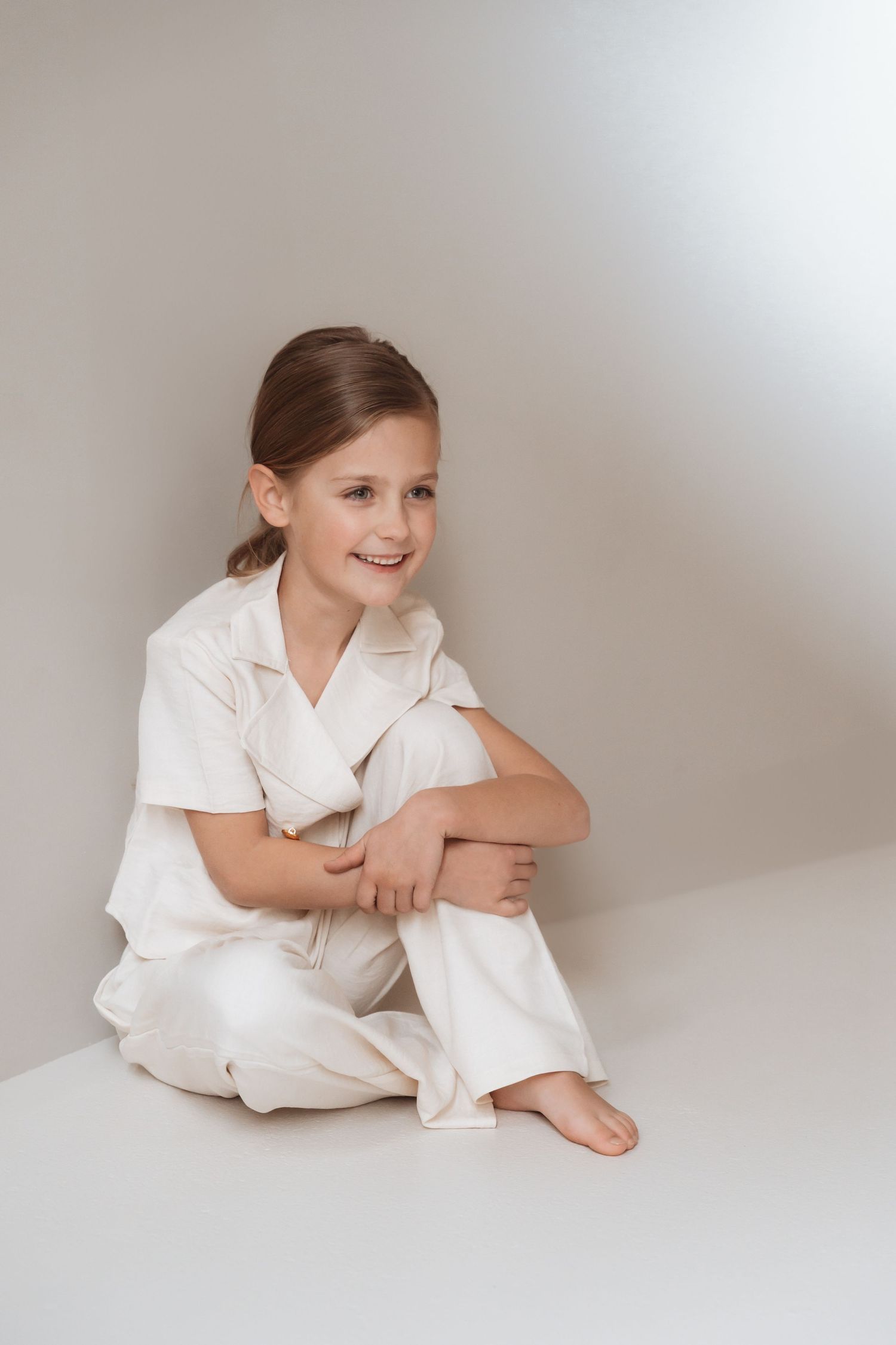 A series of candid poses in white linen loungewear against a light backdrop.