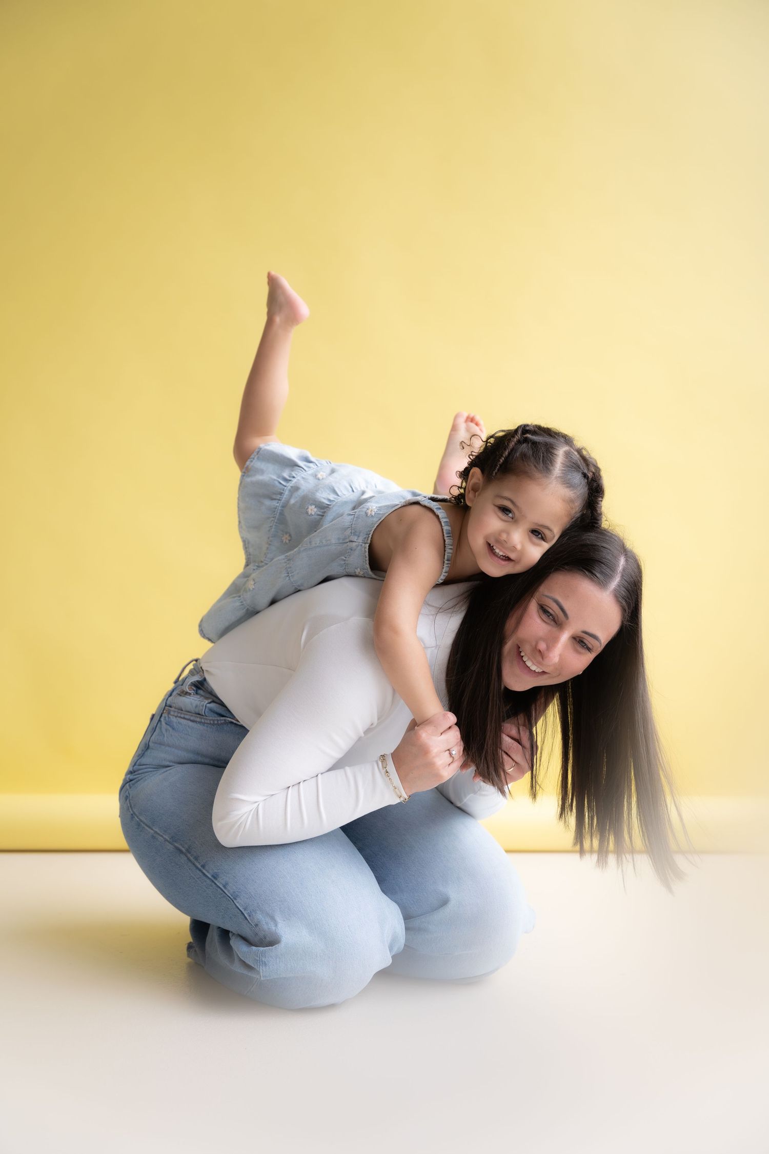 A person in a white sweater and gray pants rolls playfully on a yellow backdrop in a sequence of dynamic poses.