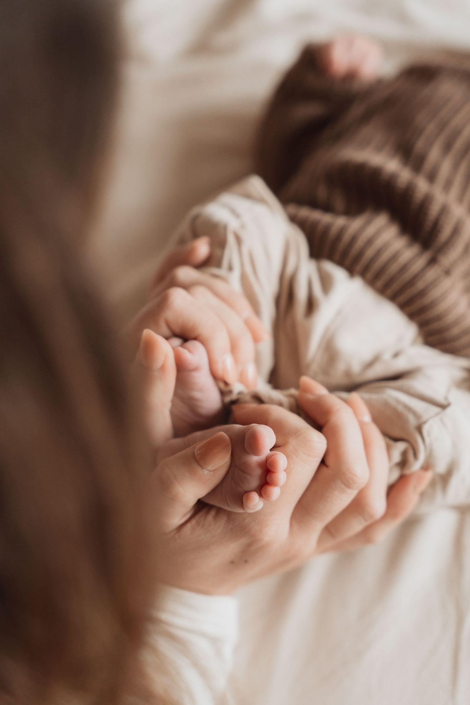 Close-up of tiny baby fingers being held gently against soft fabric.