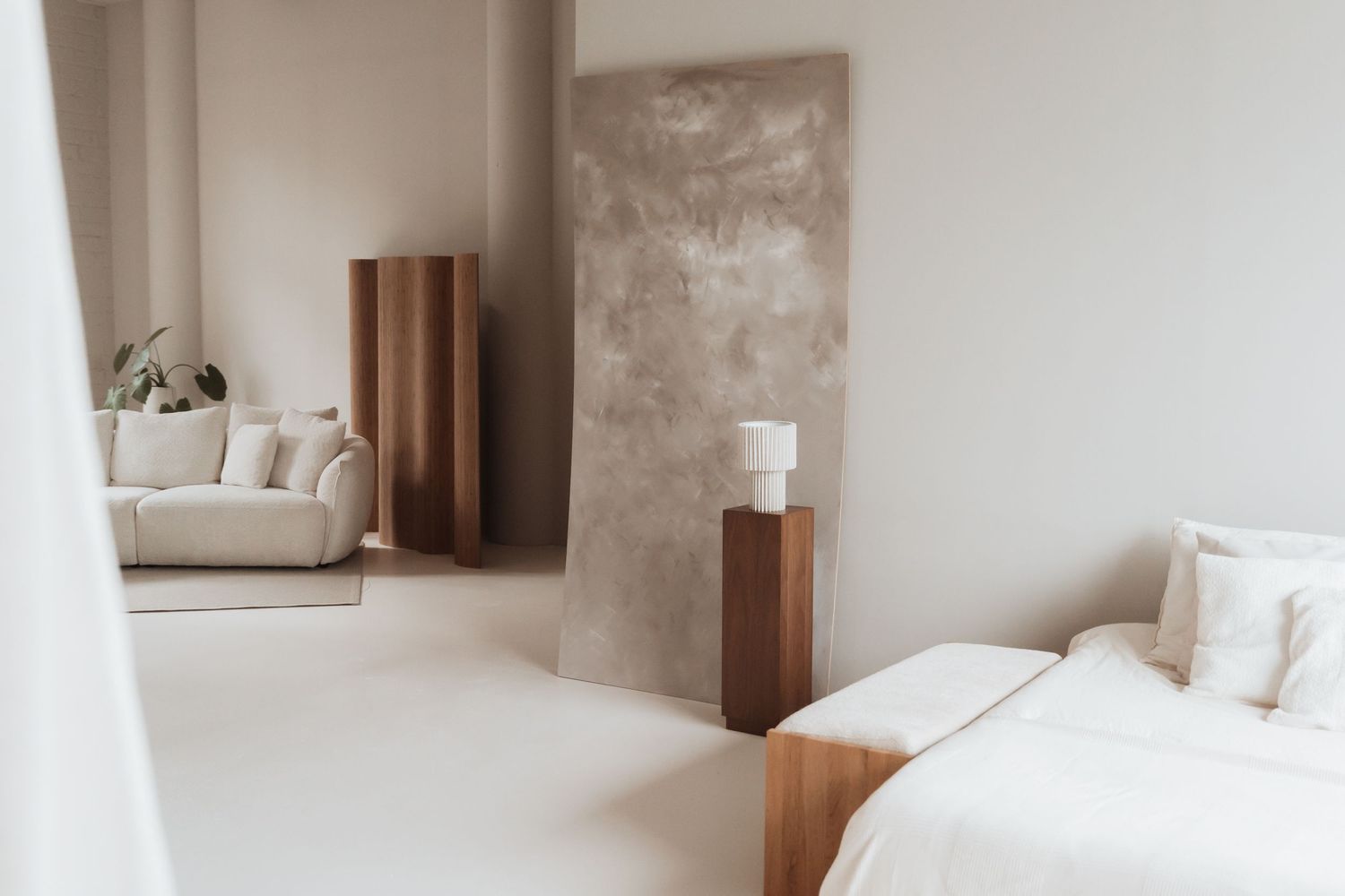 Minimalist white bedroom interior with wooden accents and natural light streaming through windows.