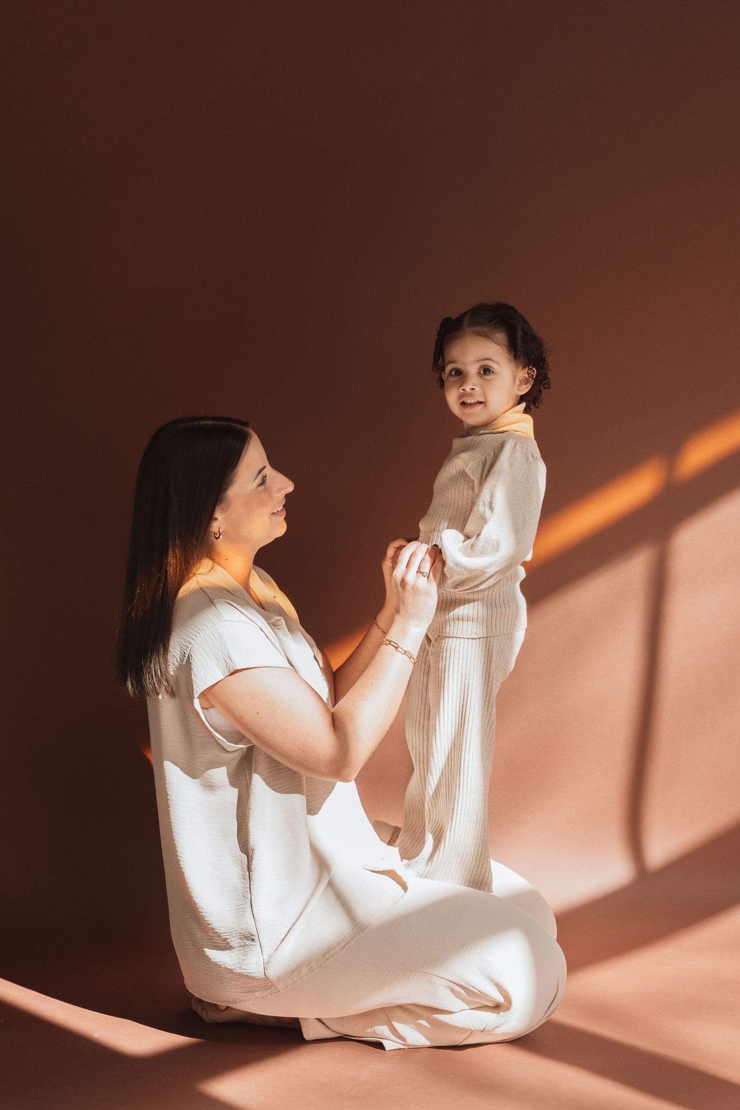 Artistic sequence of a woman in white clothing moving through dynamic poses against a brown backdrop with dramatic lighting.