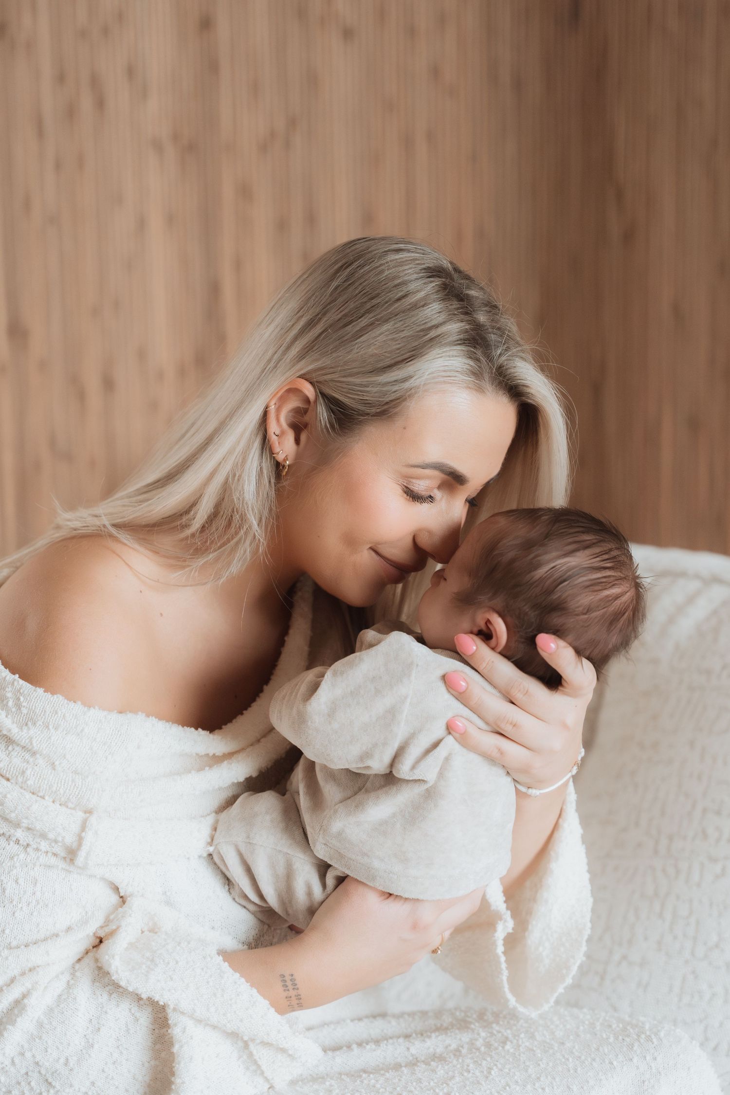 Three intimate photos in soft tones show tender moments between parent and baby in matching white outfits.