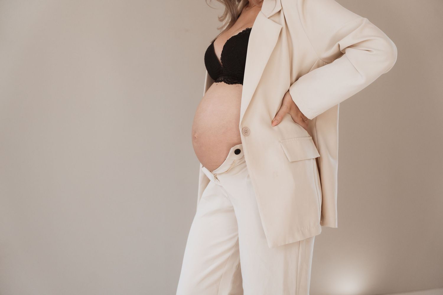 Stylish maternity fashion featuring cream colored suit and exposed belly.
