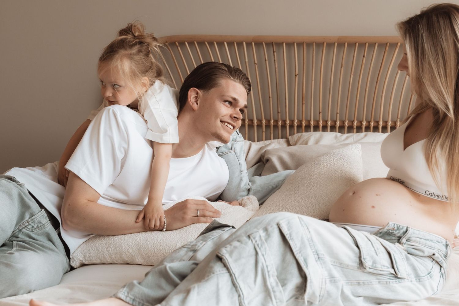 Intimate family moment captured on bed with expecting mother.