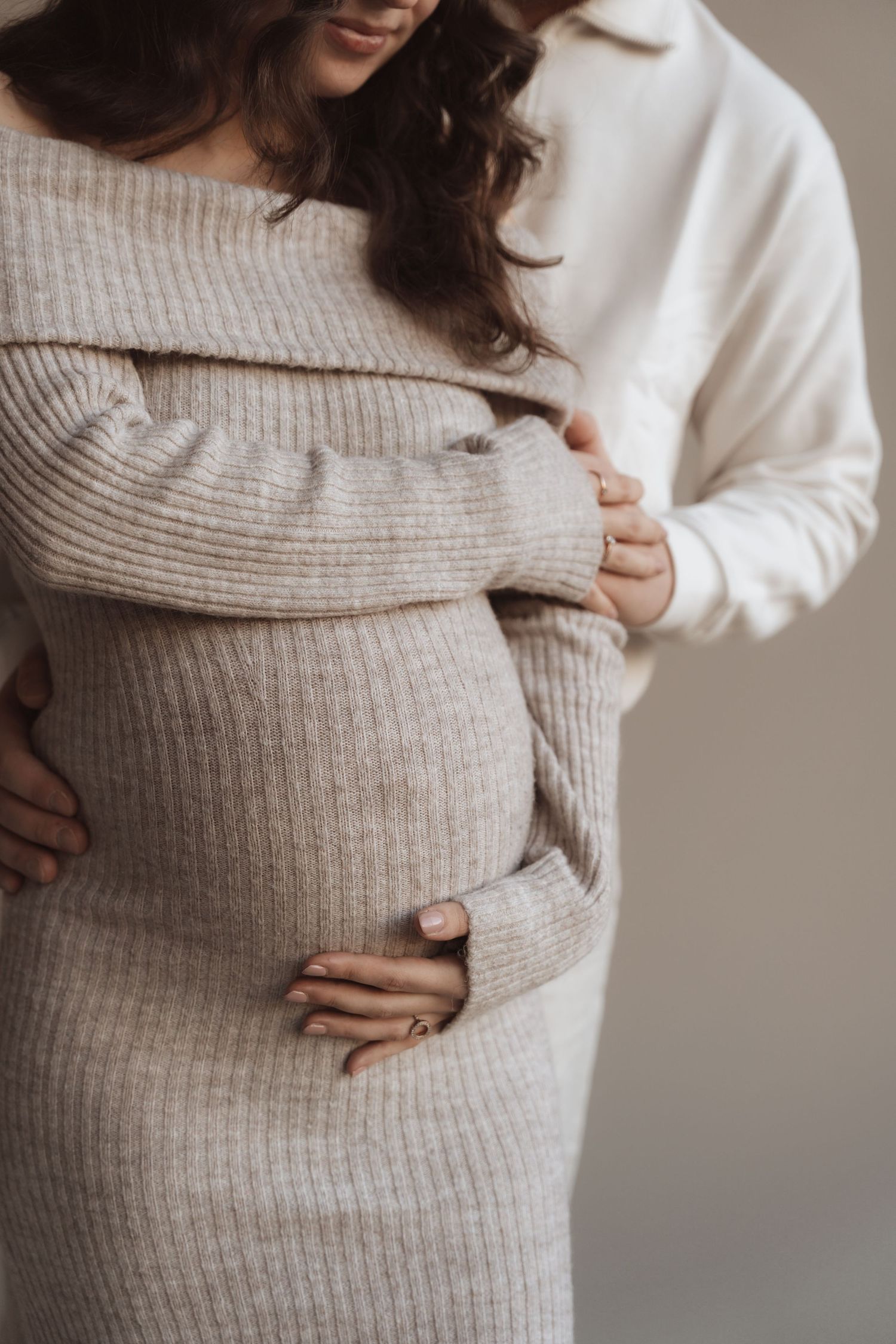 Intimate maternity moment with couple in cozy knit sweaters.
