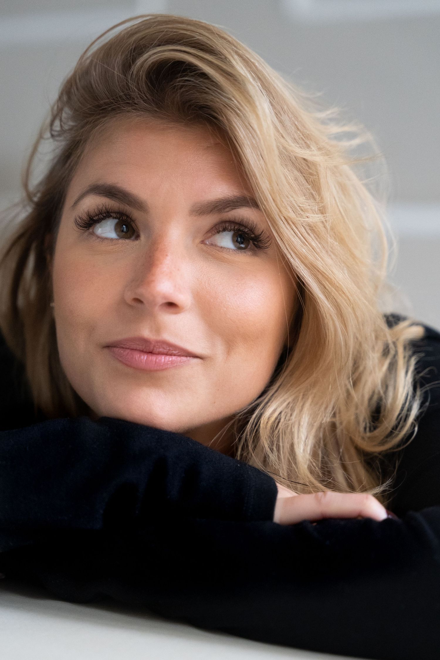 Close-up beauty portrait with soft lighting and natural makeup against light background.