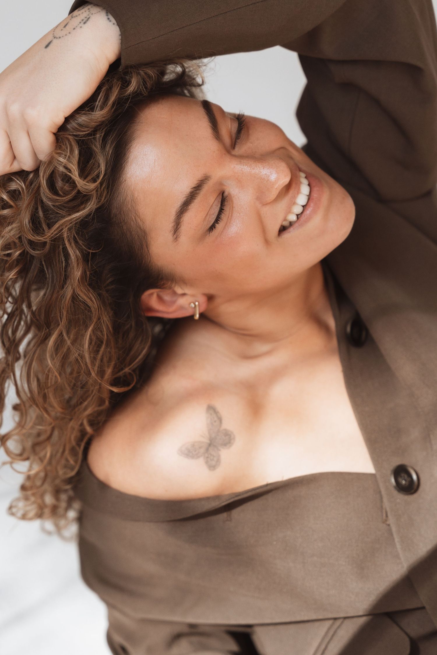 Natural portrait series in brown sweater showing joyful expressions and butterfly tattoo.