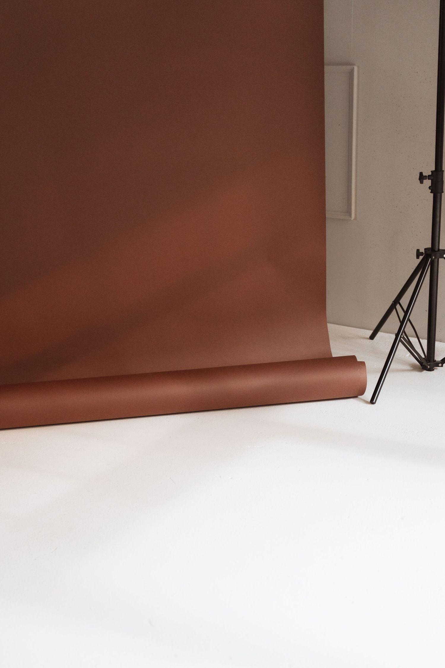 Photography studio setup with brown seamless paper backdrop against white walls and floor.