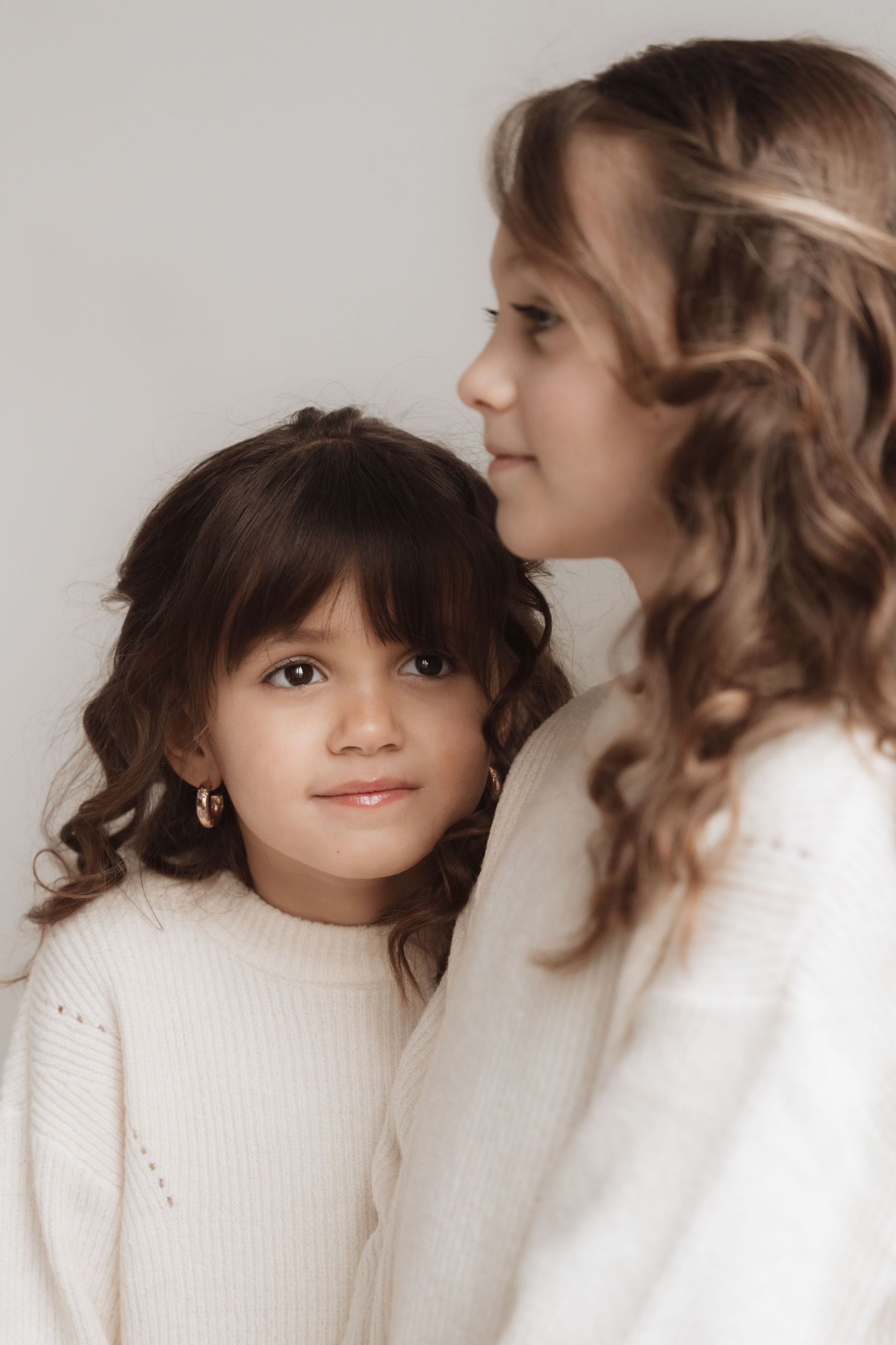 Four sequential photos showing a person with dark bangs and curly hair wearing a white sweater against a light background.