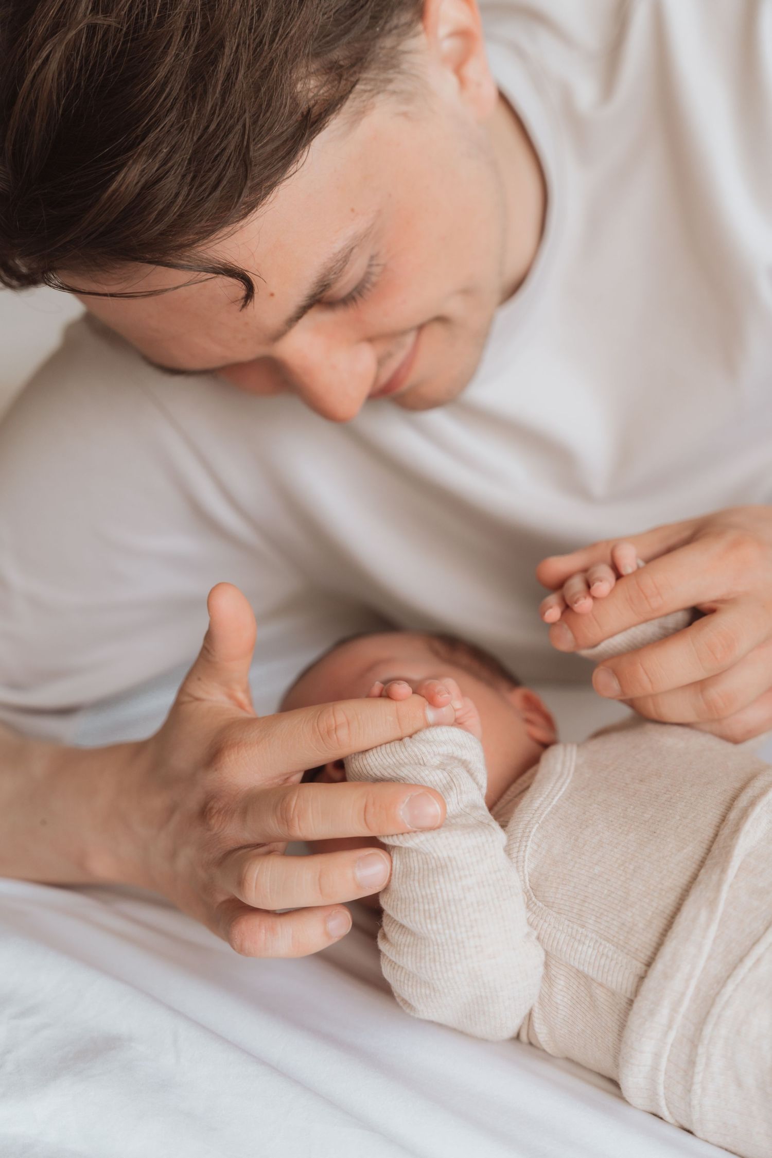 Intimate close-up photograph of gentle touch against cream colored fabric.