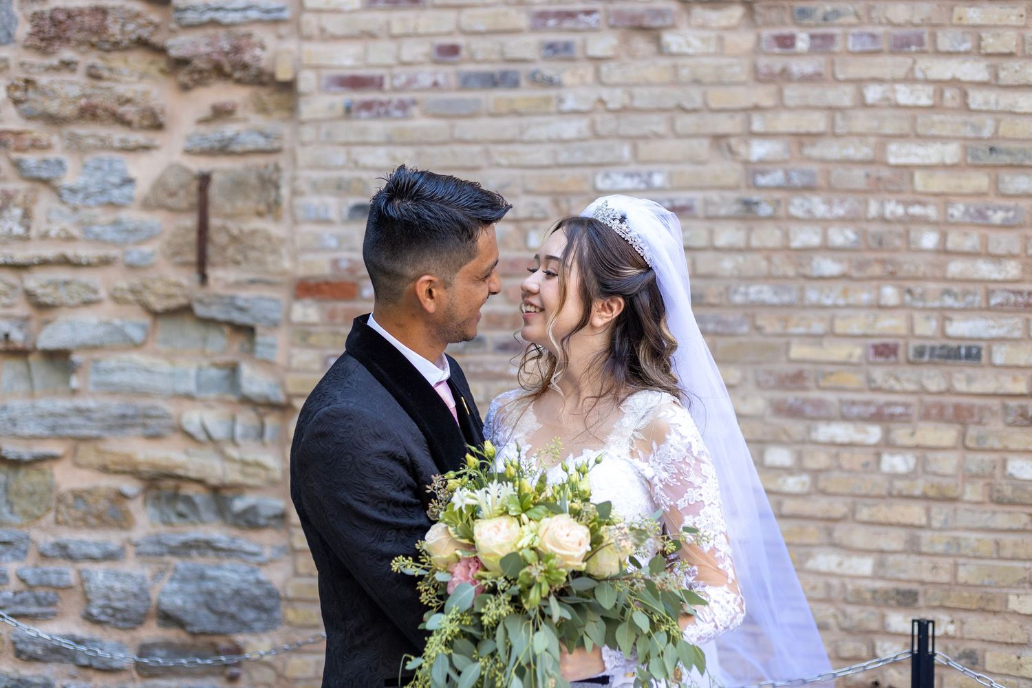 Bride and groom embracing in front of stone wall with bouquet in Minneapolis