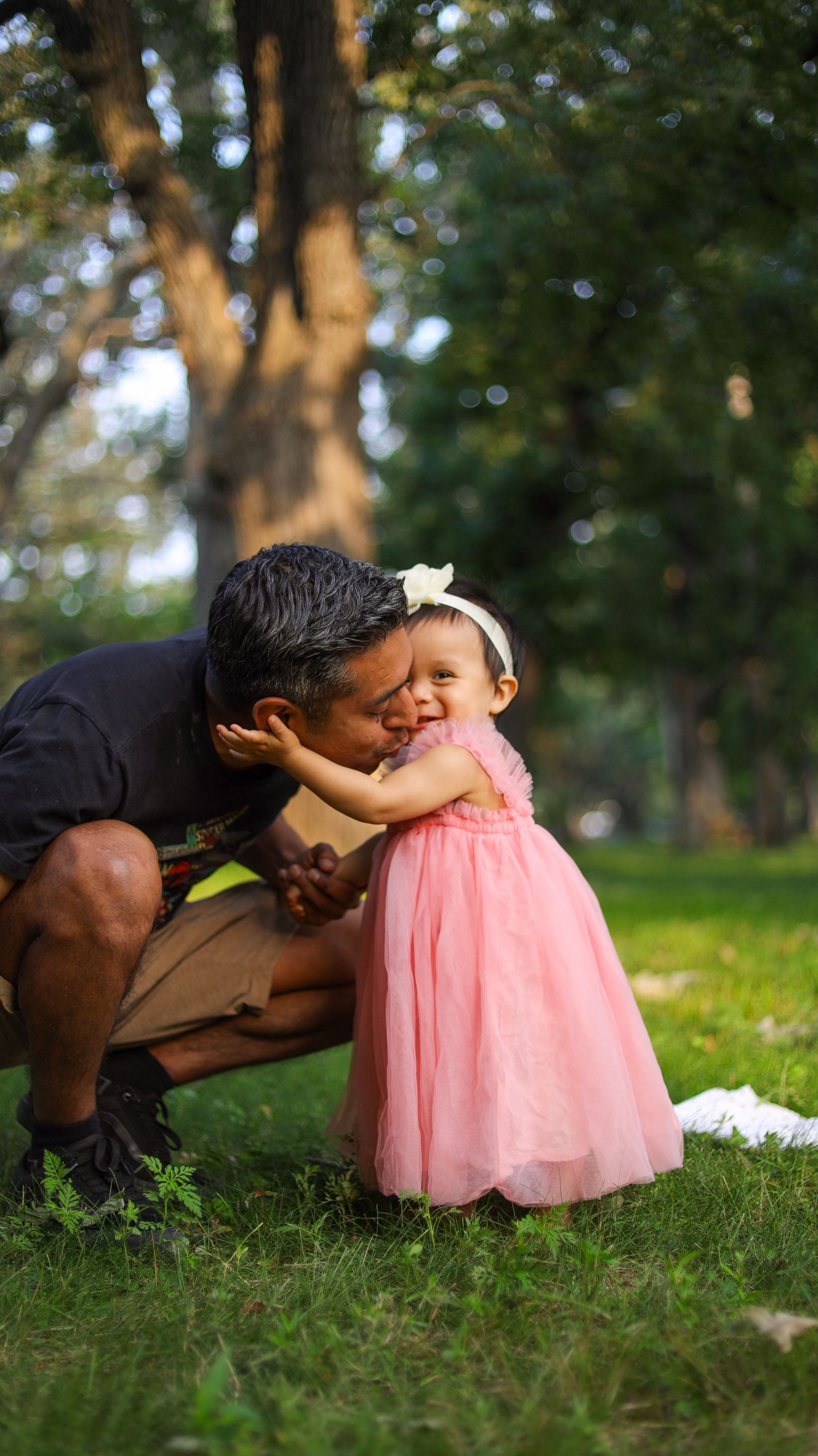 Toddler girl standing in pink dress on grass during outdoor portrait session in Minneapolis with her father.
