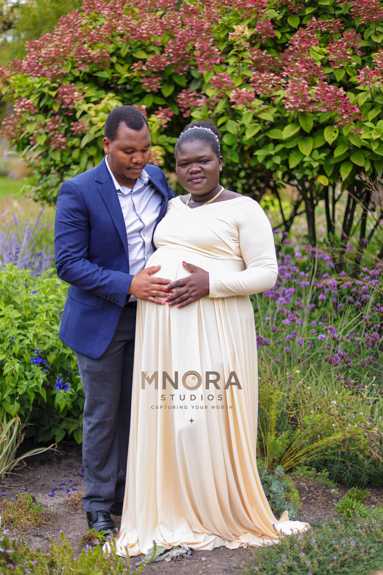 Couple posing together in garden during outdoor maternity session in Minneapolis