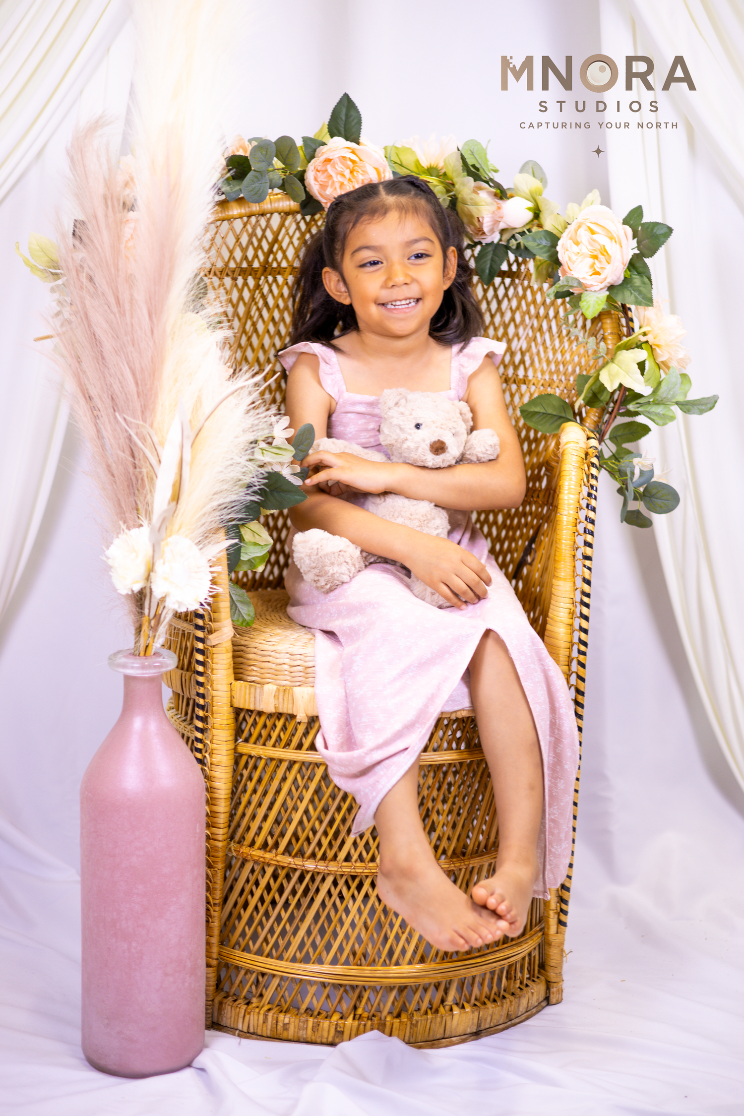 Full-length studio portrait of young girl in pink dress with floral backdro