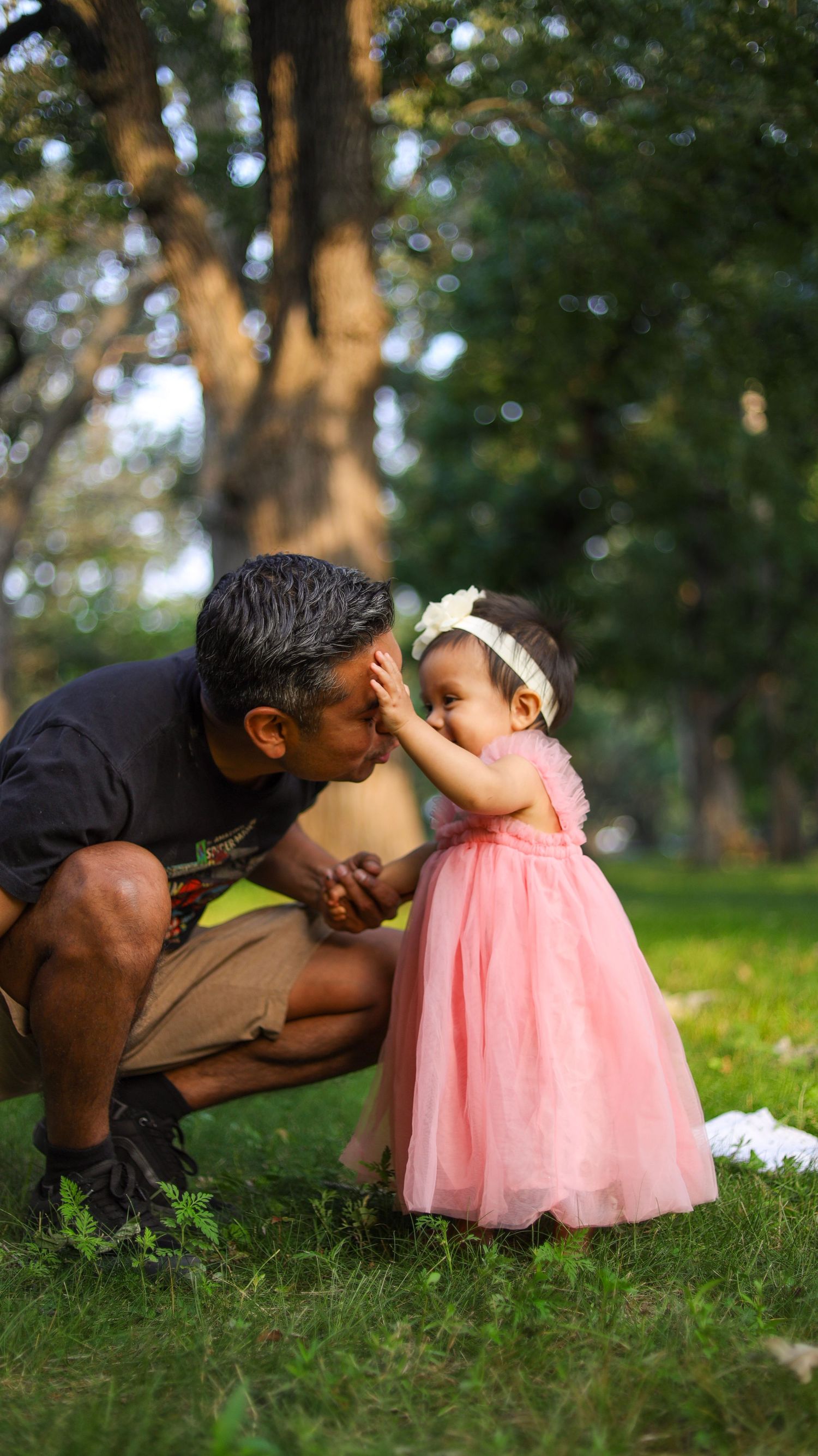 Toddler girl standing in pink dress on grass during outdoor portrait session in Minneapolis with her father.