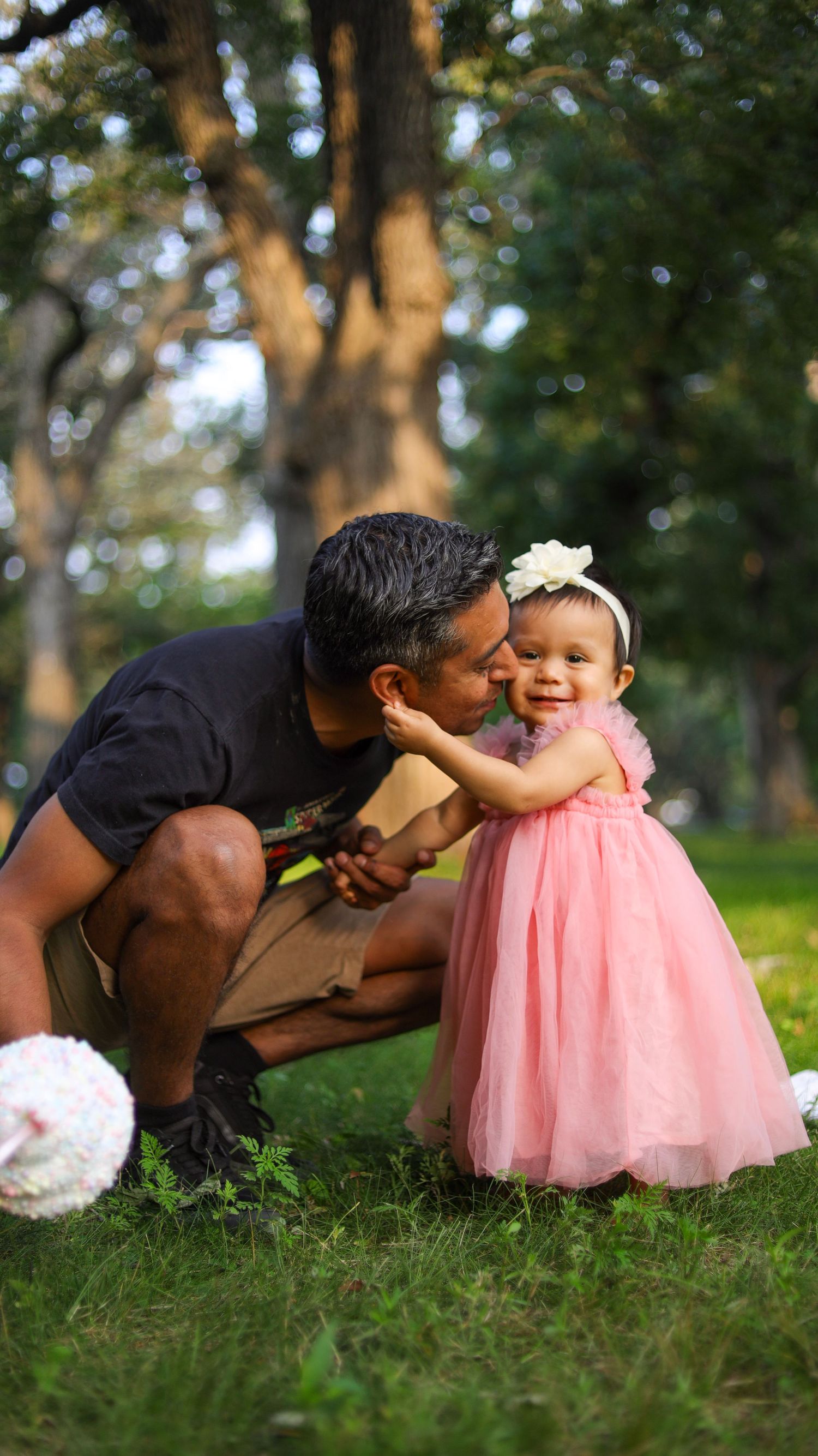 Toddler girl standing in pink dress on grass during outdoor portrait session in Minneapolis