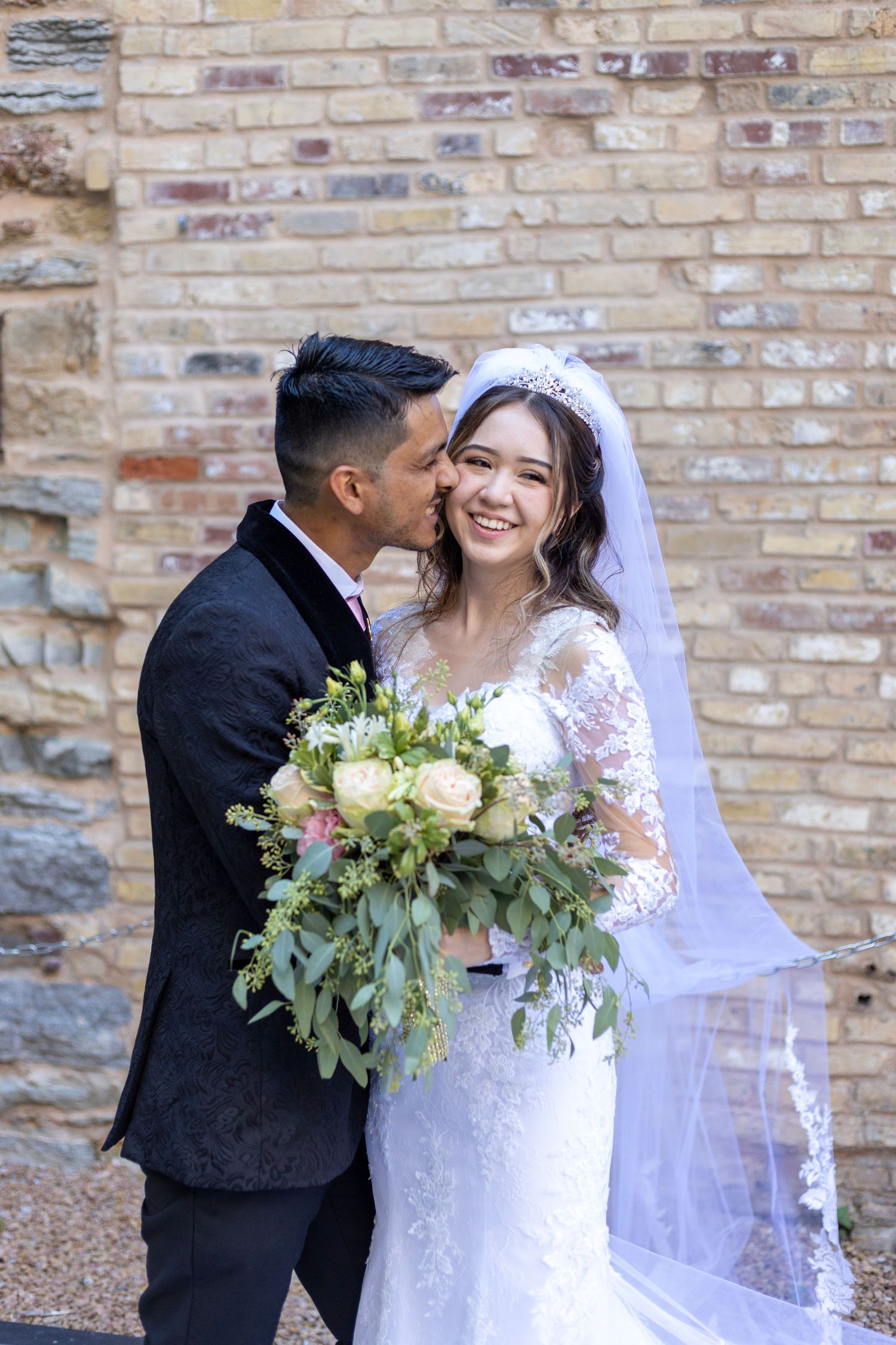 Newly married couple posing in front of stone wall with bouquet in Minneapolis