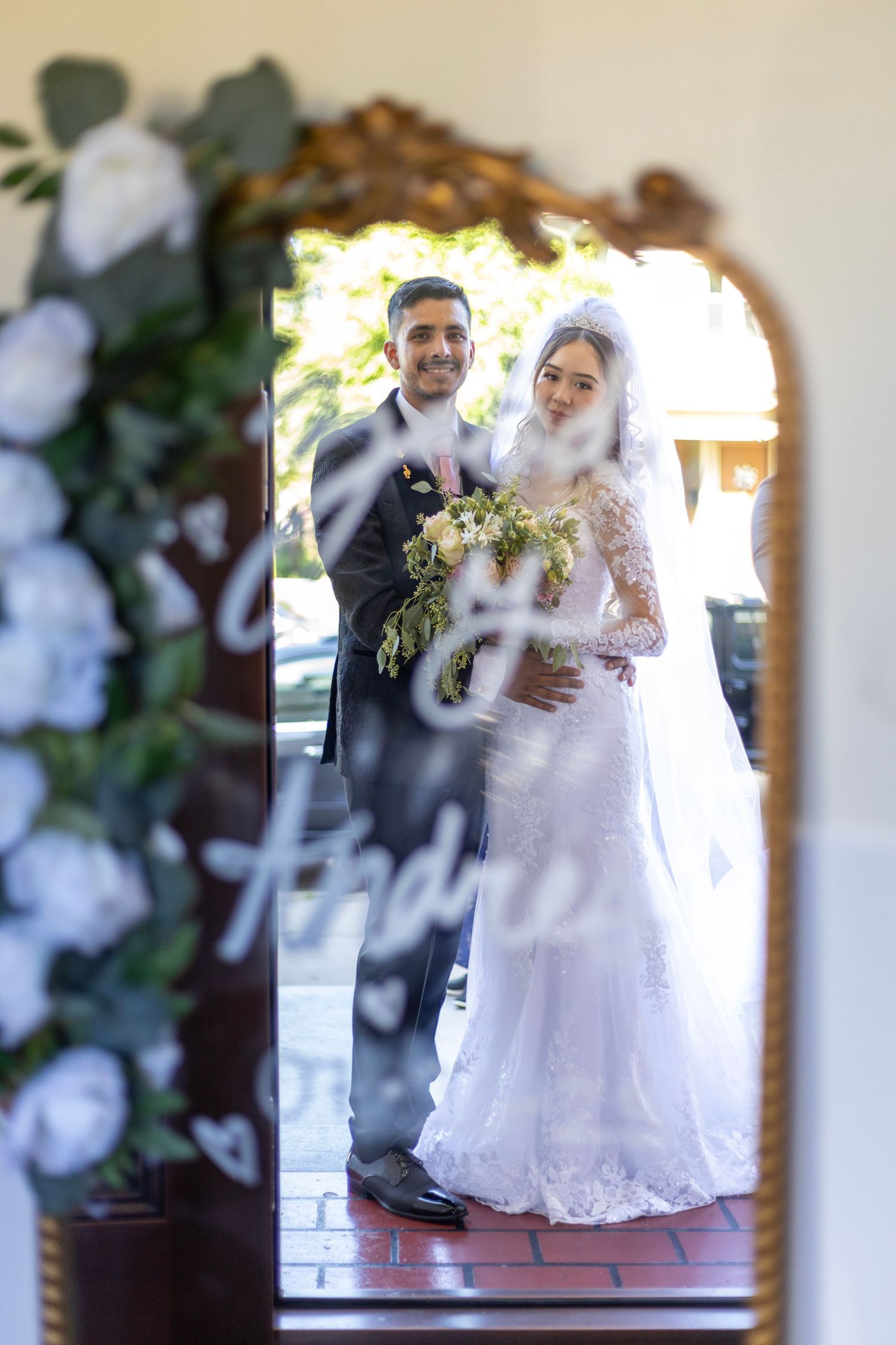Wedding portrait of couple standing under floral archway