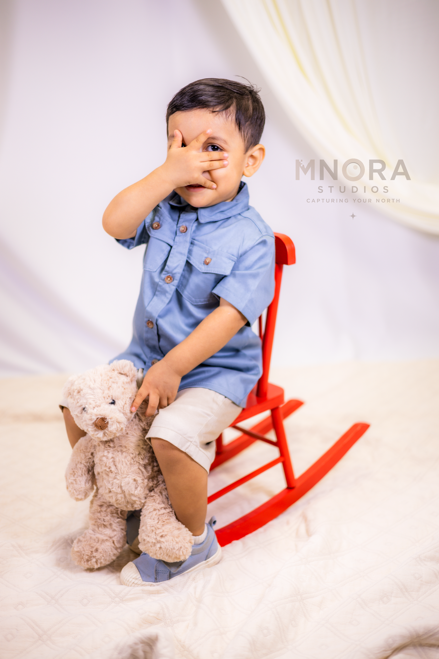 Toddler boy on red rocking horse during studio portrait session in Minneapolis