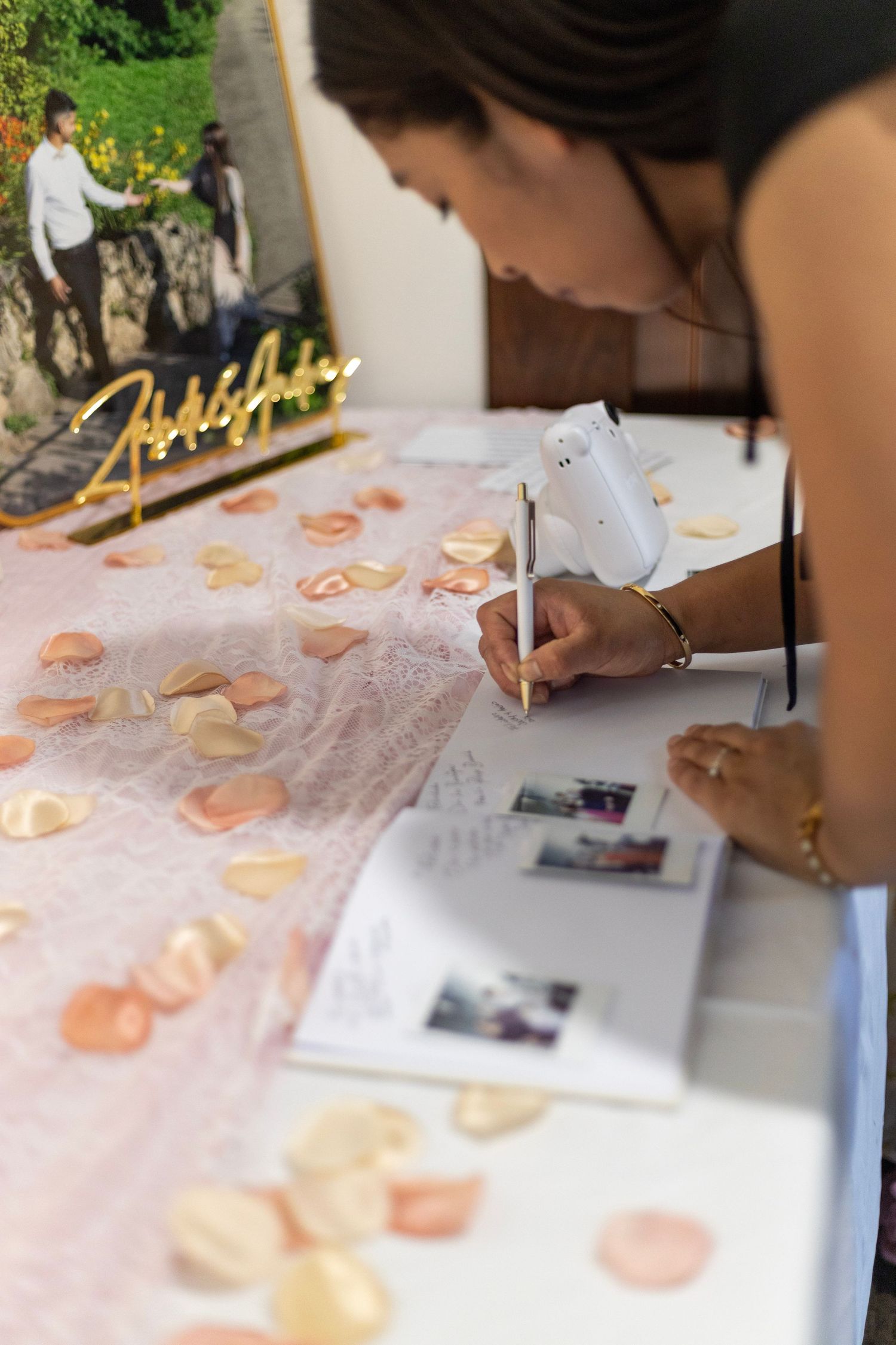 Guest signing wedding guestbook at reception table