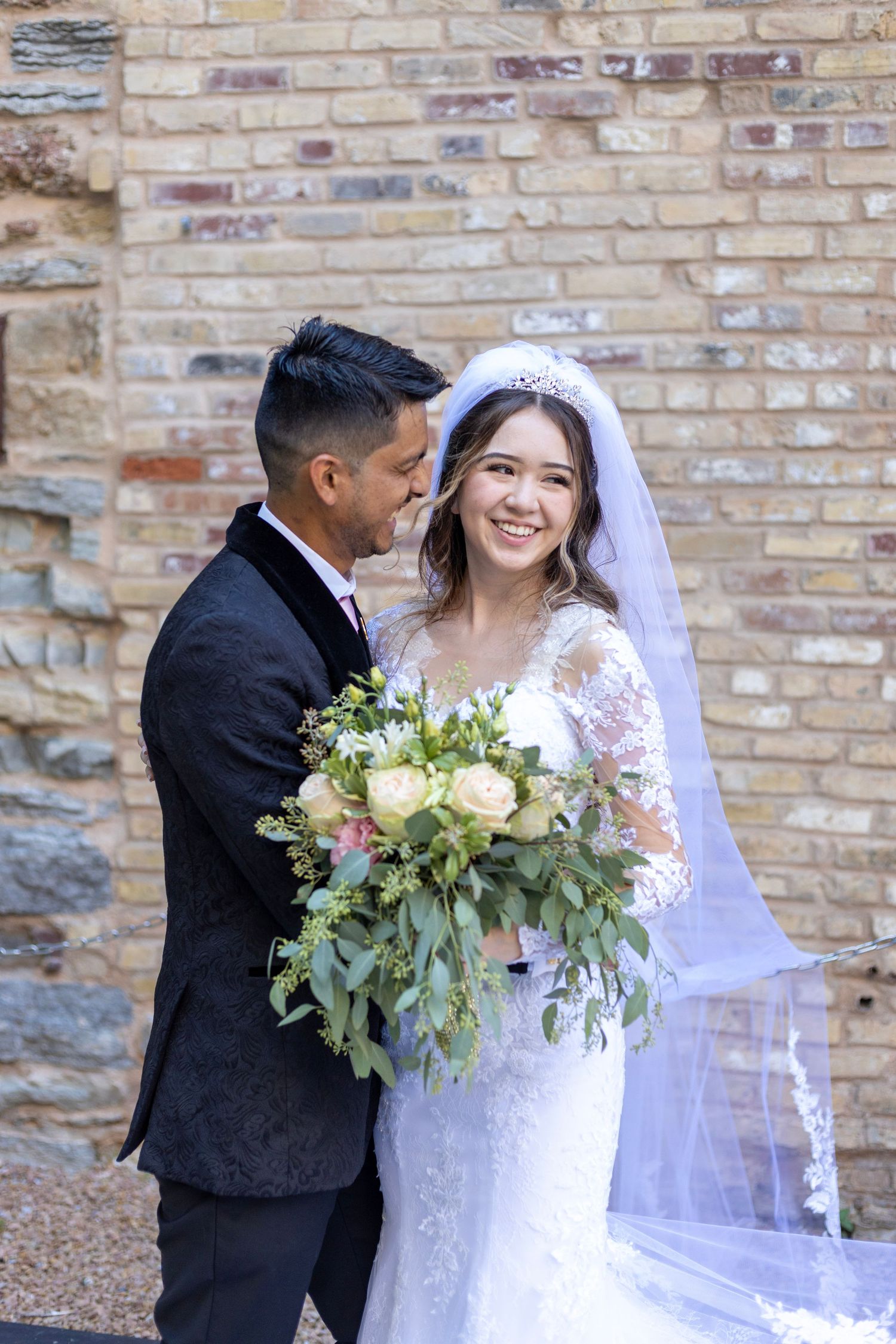 Bride and groom smiling in front of stone wall during Minneapolis wedding portrait
