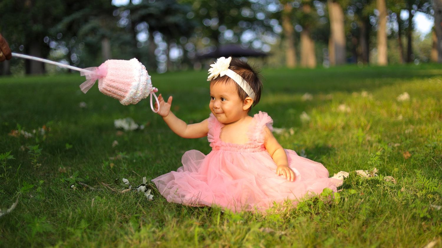 Toddler girl in pink dress holding cotton candy during outdoor portrait session