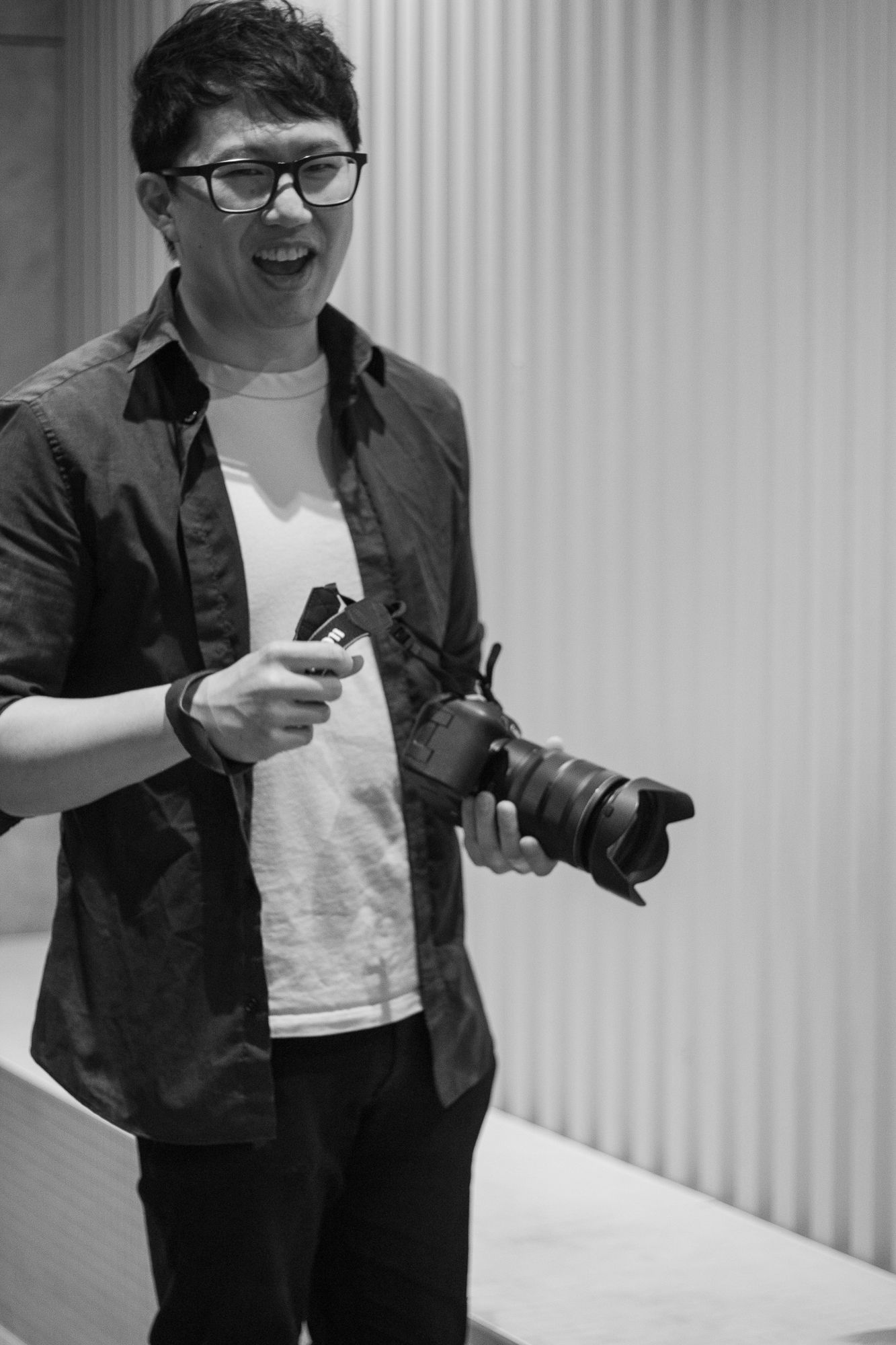 David, owner of DFU Photos, holding a camera and laughing during a photography session in Auckland