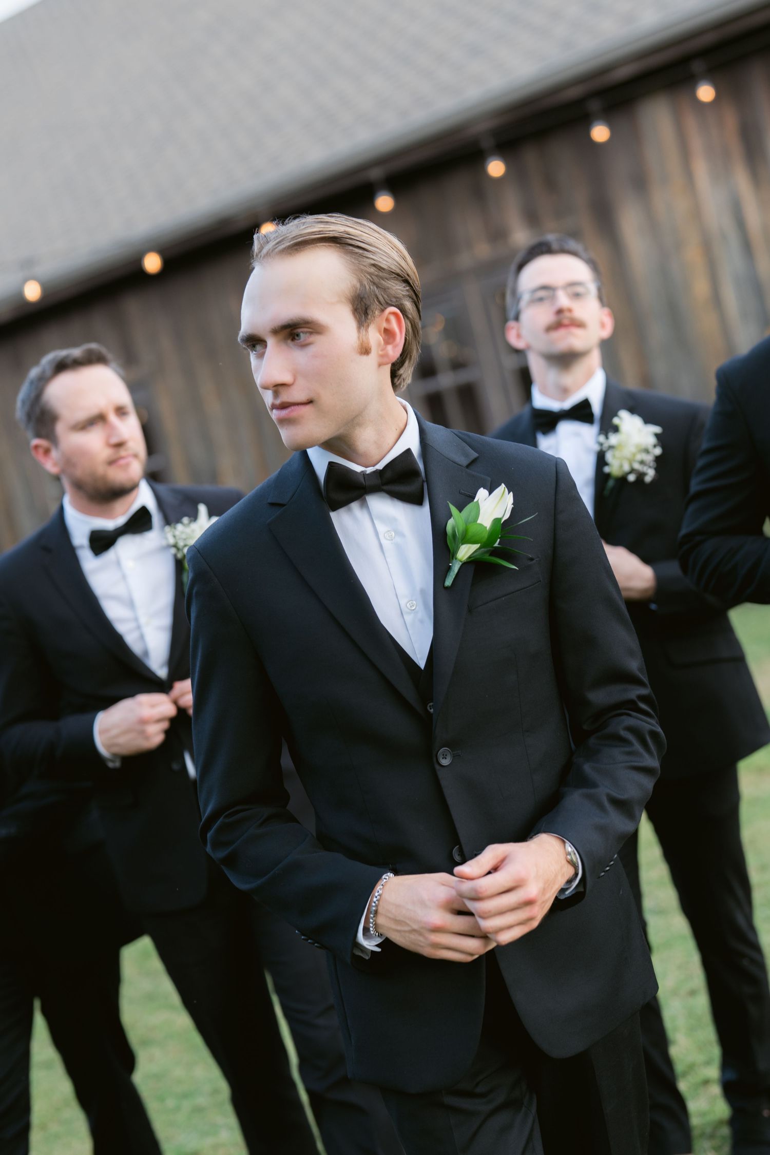 Groomsmen in black tuxedos and bowties pose casually outdoors at a wedding reception in Richmond, captured by Bowe Photo Co