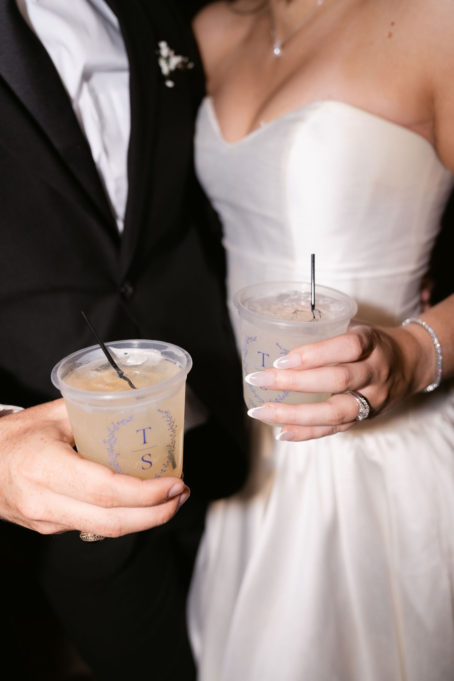 Bride and groom holding personalized monogrammed cocktail cups with straws at their wedding reception.