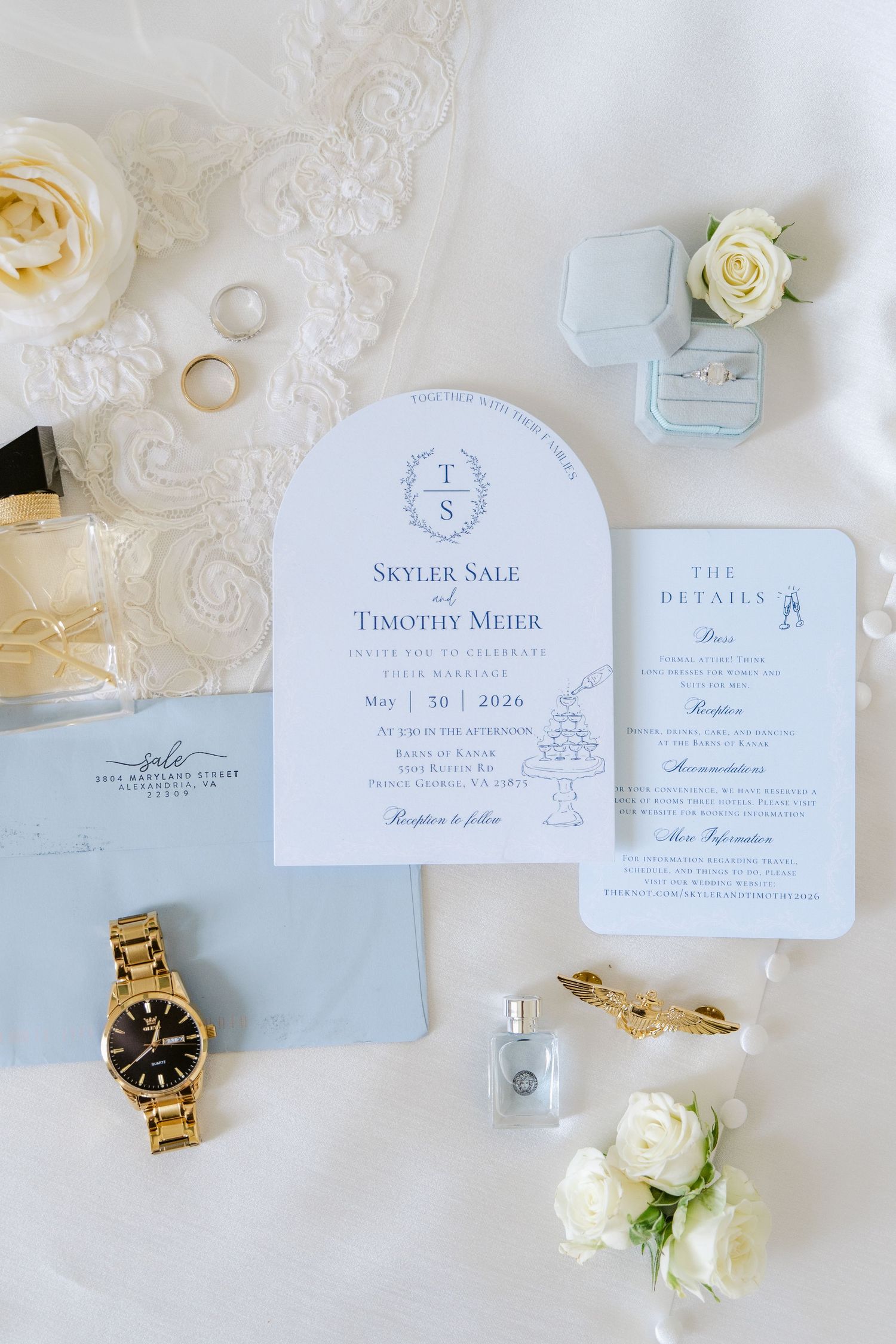 Elegant wedding invitation suite for Skyler Sale and Timothy Meier with gold watch, rings, perfume, and white roses on white fabric.