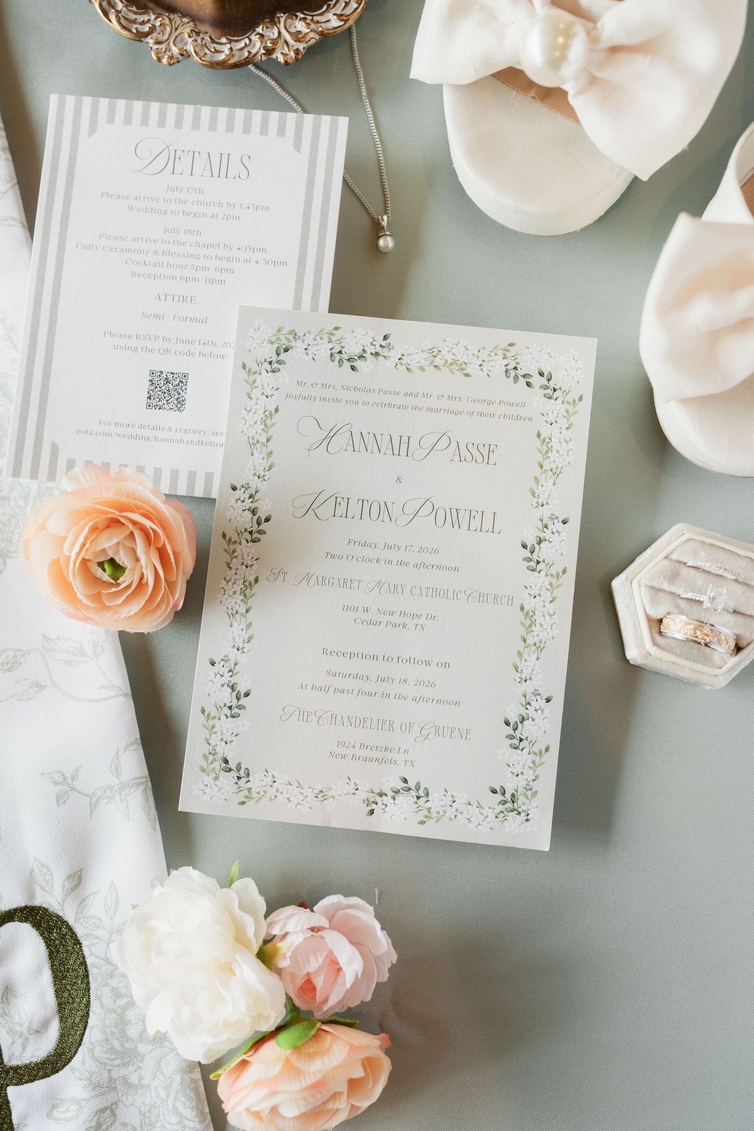 Elegant wedding invitation suite with floral border, rings, peach roses, and bridal accessories on a soft blue background.