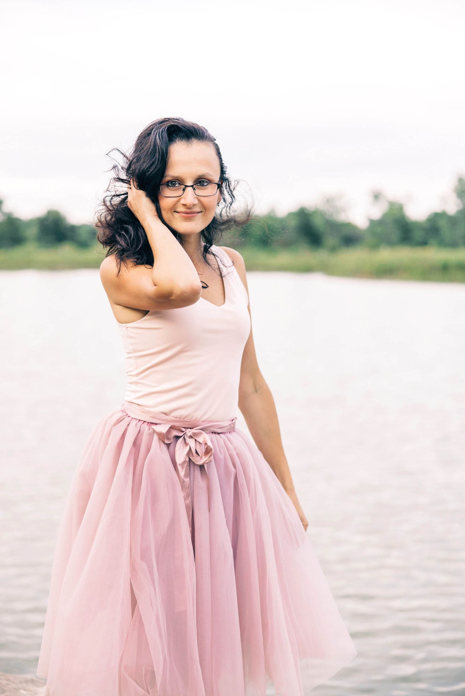 Portrait of a woman in pink tulle dress playing by waterfront in dreamy summer portrait session in Seattle.