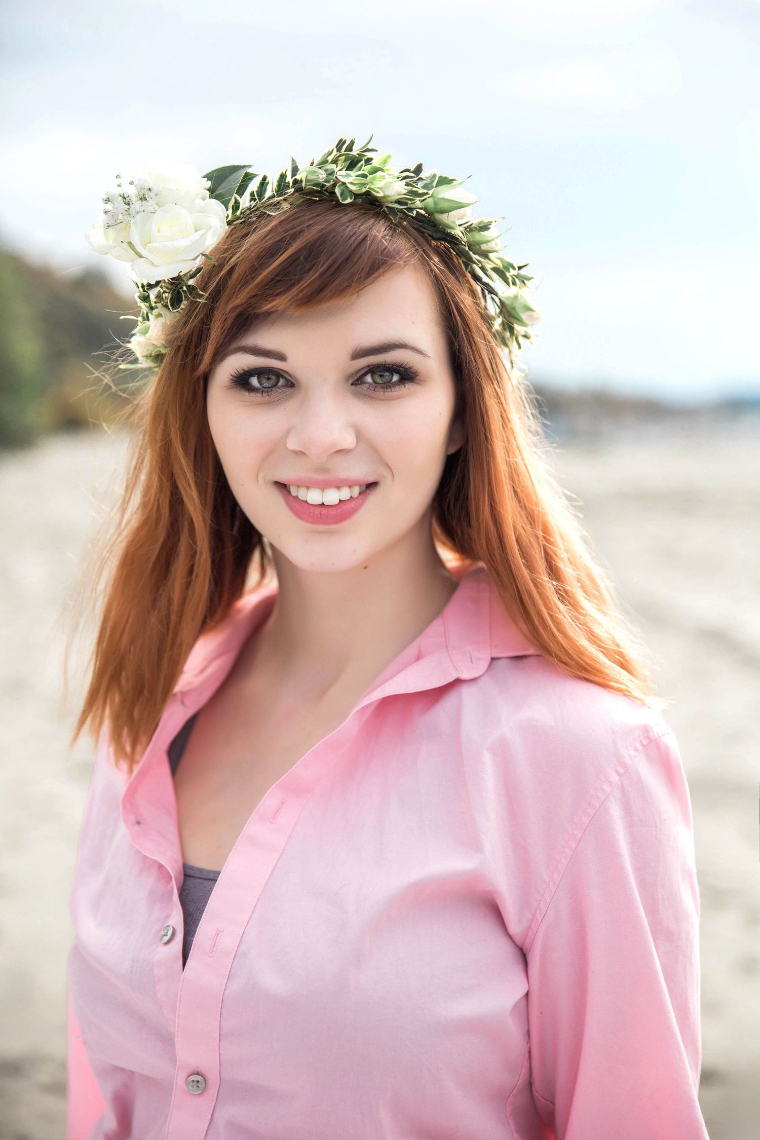 Portrait of a girl wearing pink shirt and floral crown poses outdoors in natural lighting at Golden Gardens in Seattle.