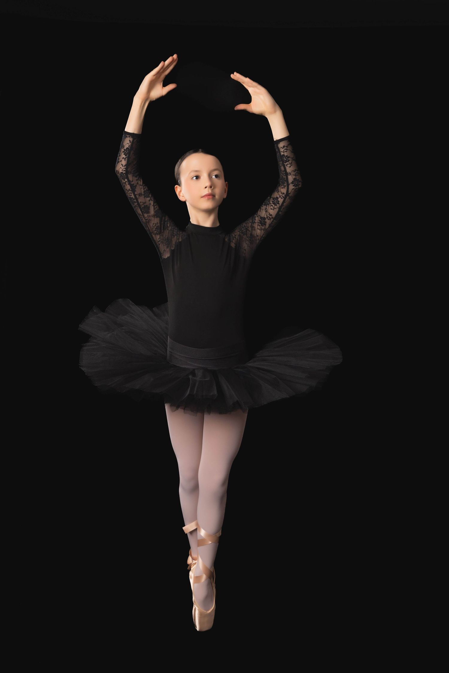 Ballerina portrait in black leotard and tutu performing graceful dance poses against dark background.