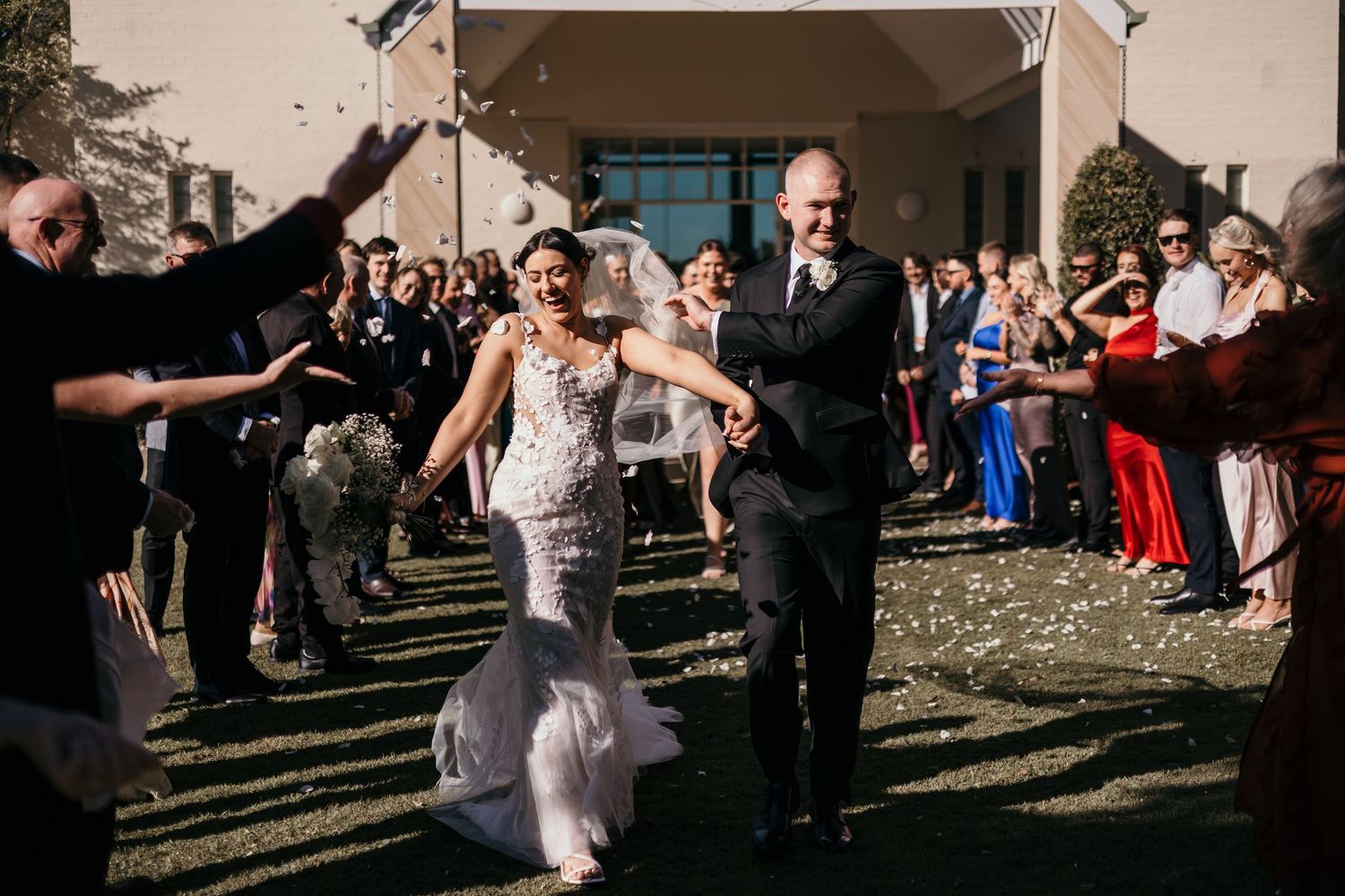 Wedding guests dance and celebrate together on an outdoor patio during a festive reception party.