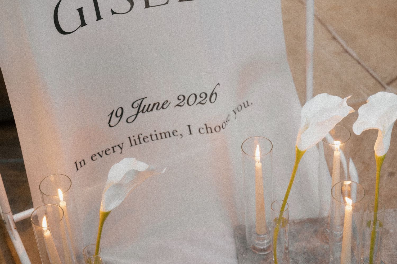 Elegant wedding sign with white calla lilies and candles reading In every lifetime I choose you dated June 19 2026.