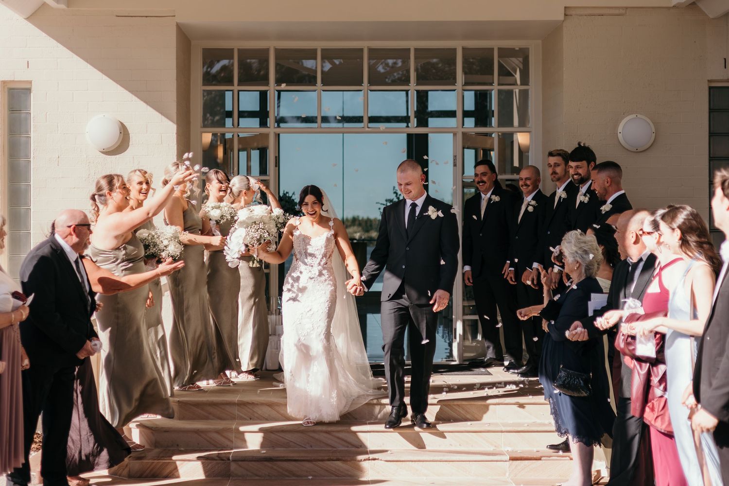 Wedding guests stand in a hallway watching a couple share their first dance at an elegant venue reception.