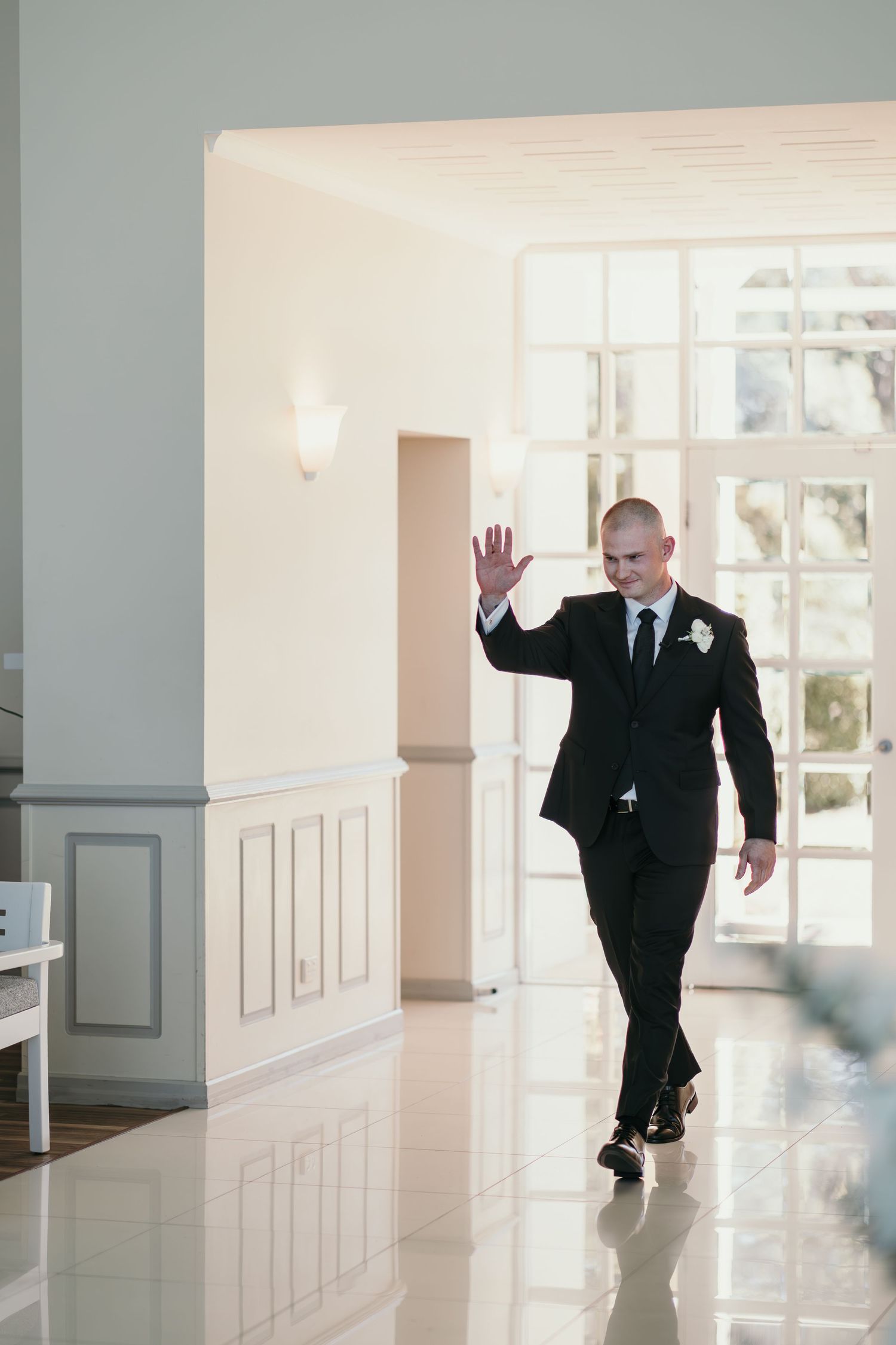 A sequence of photos showing a person in a black suit crawling across a polished white floor in an elegant hallway.