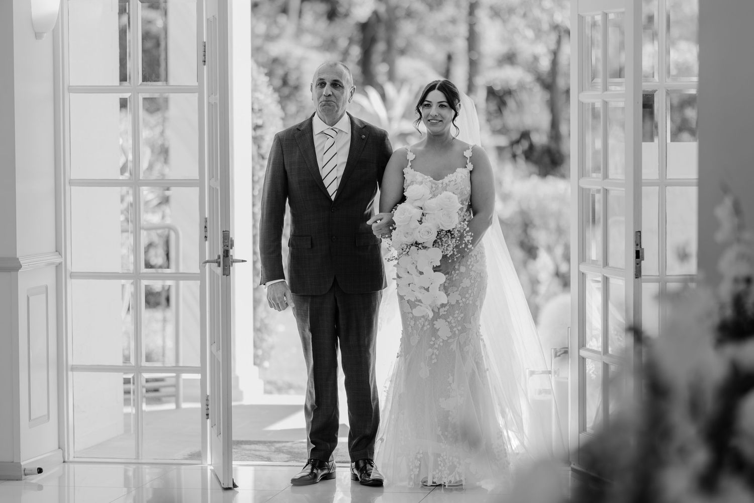 A black and white wedding photo collage showing couples walking through elegant French doors and garden settings.