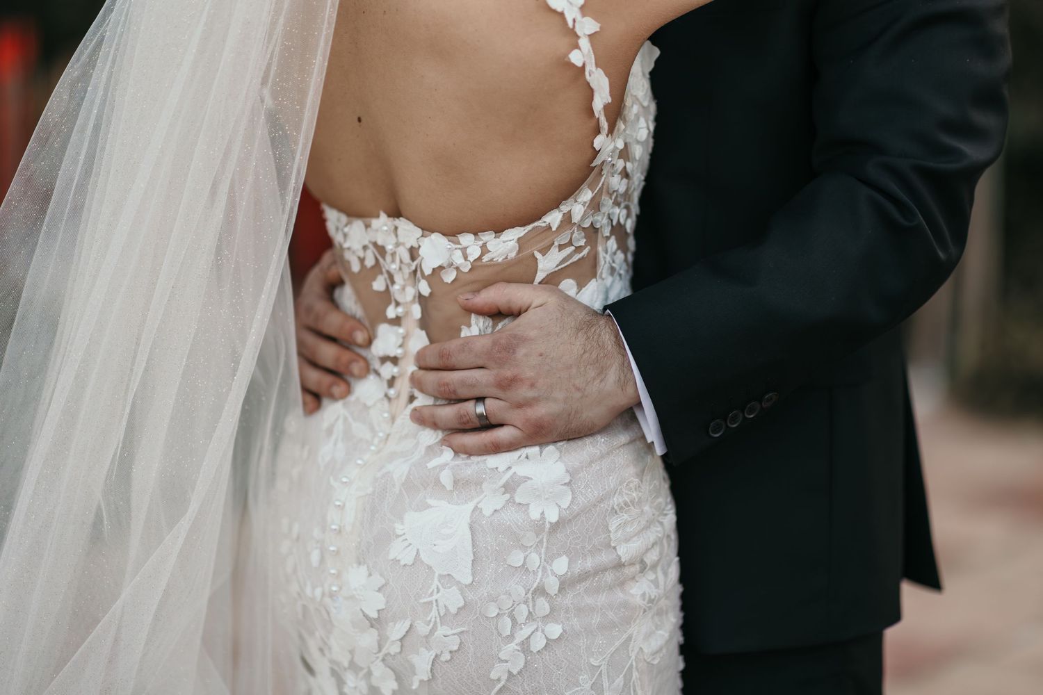 A bride and groom embrace in formal wedding attire during their wedding ceremony.