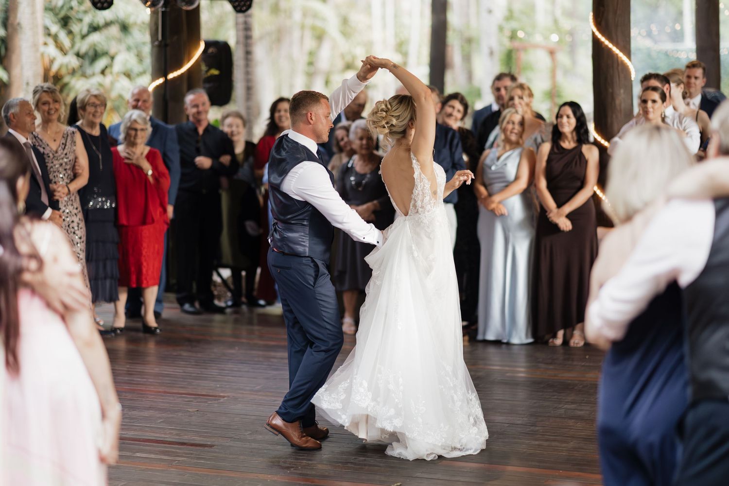 Bride and groom share first dance at wedding reception surrounded by guests in elegant venue.