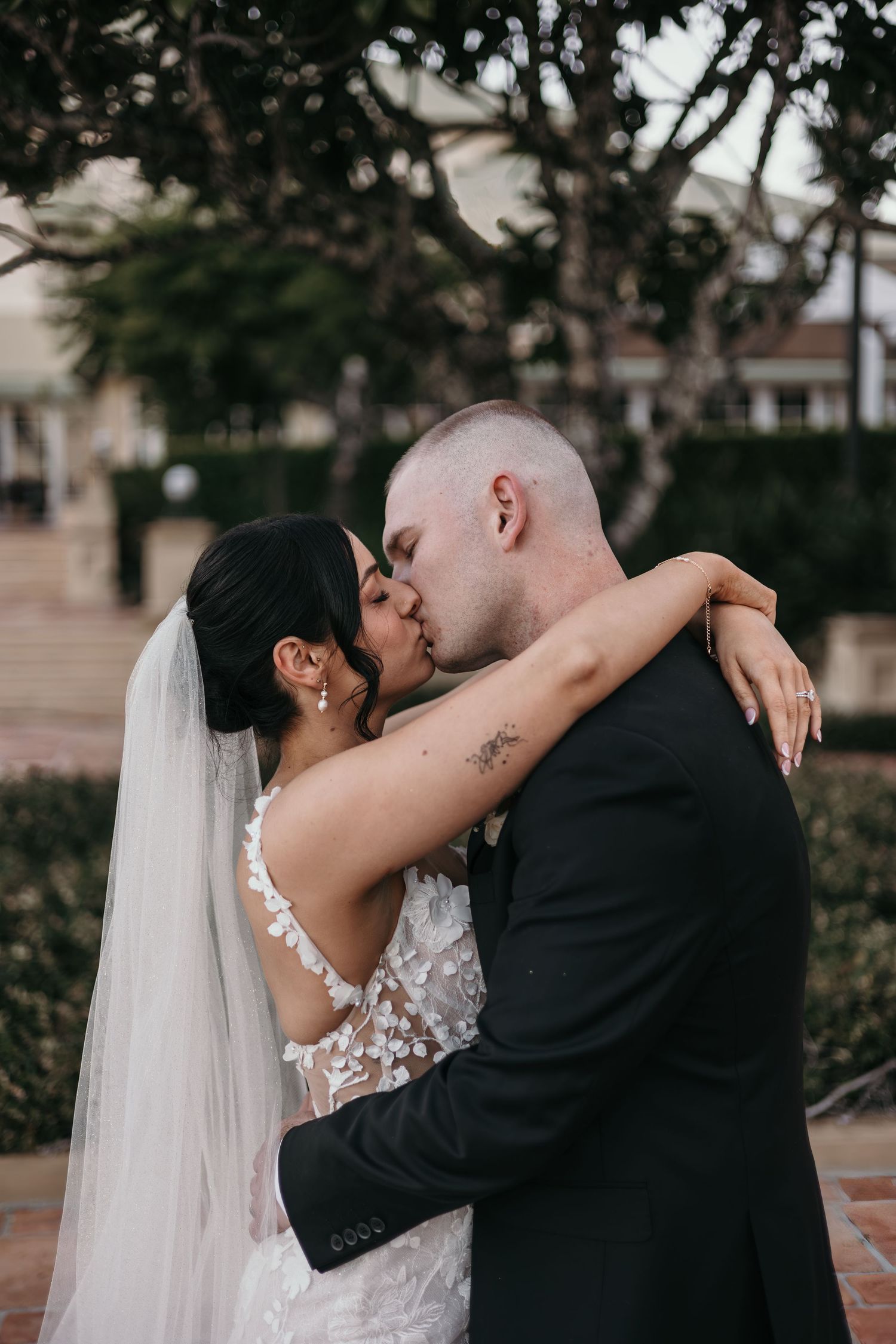 A romantic series of wedding photos showing a bride and groom sharing tender kisses in an outdoor garden setting.