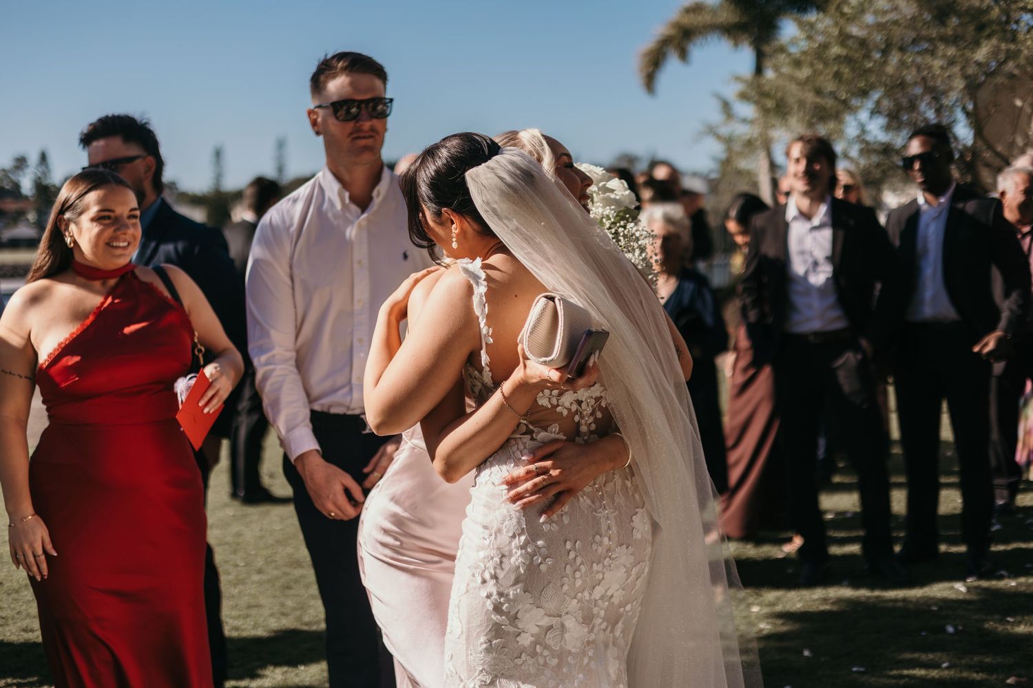 Wedding guests dance and celebrate during an outdoor reception with burgundy and neutral color scheme.