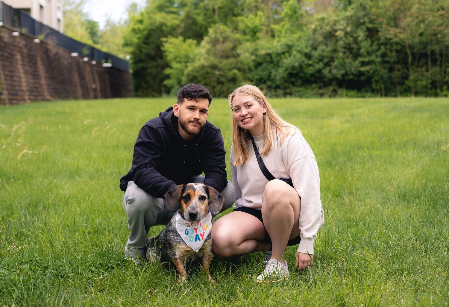 A couple sits in a grassy meadow with their Australian cattle dog on a sunny spring day.