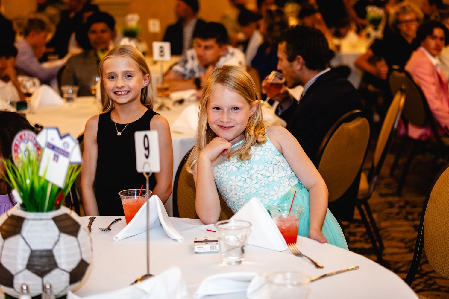 Two young guests seated at a formal dinner table with soccer ball centerpiece.