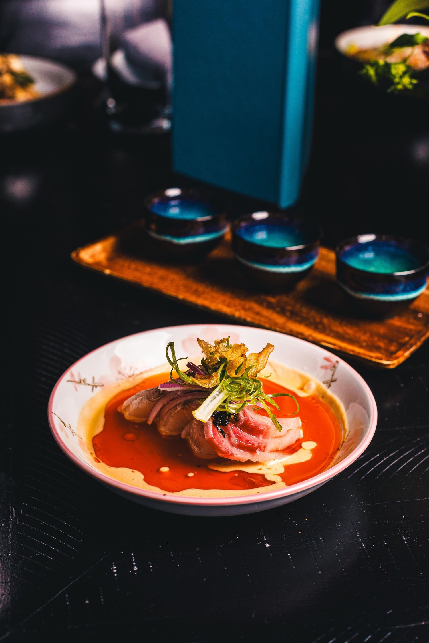Elegant Japanese ramen bowl with sliced meat, pickled vegetables, and broth, served in a fine dining restaurant setting.