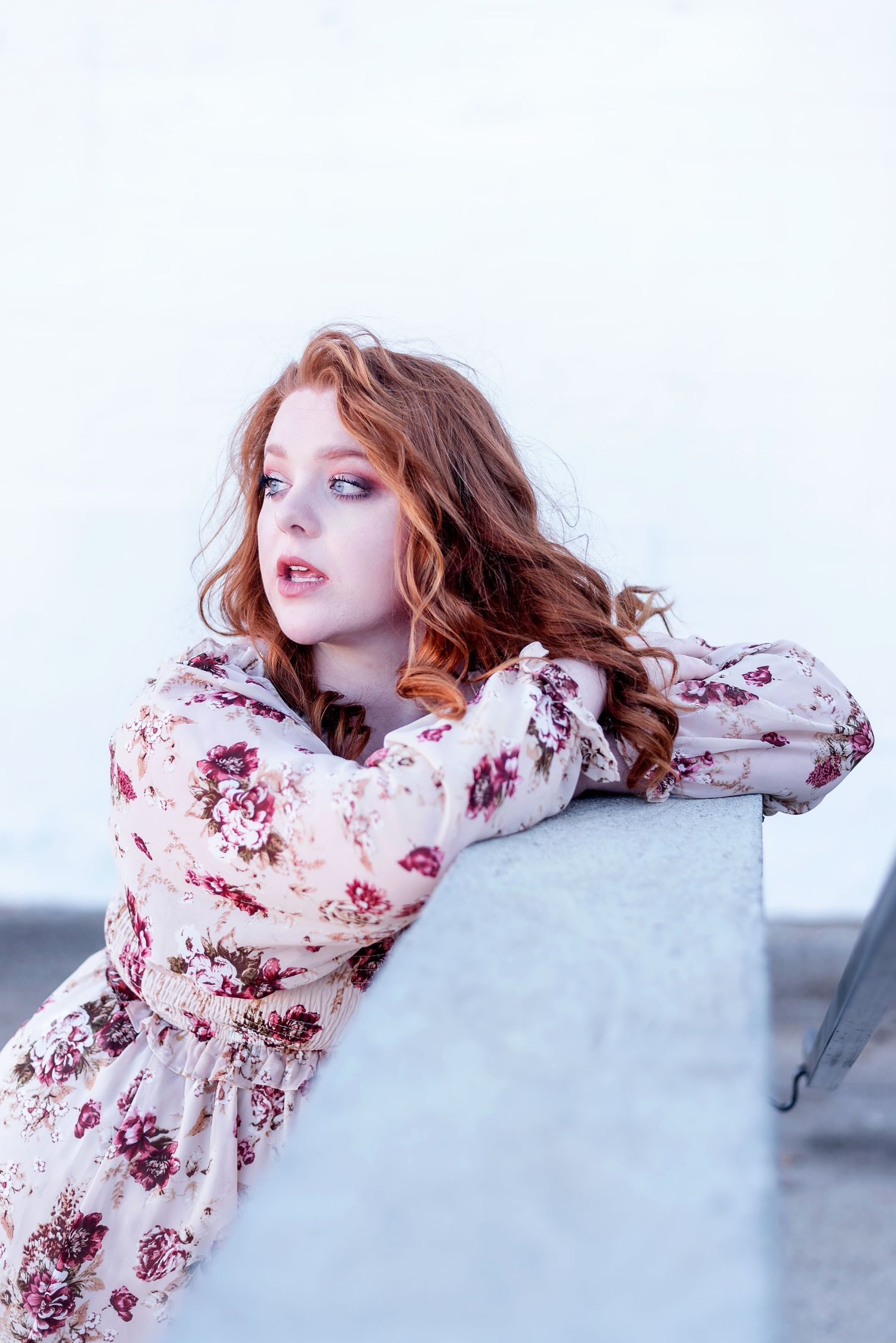 Fashion portrait featuring floral dress against light background.