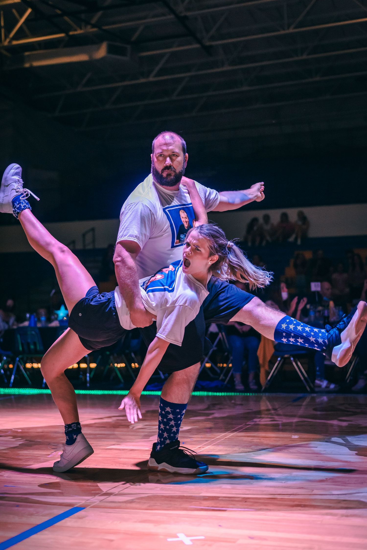 Dancers performing synchronized moves on illuminated stage floor during performance.