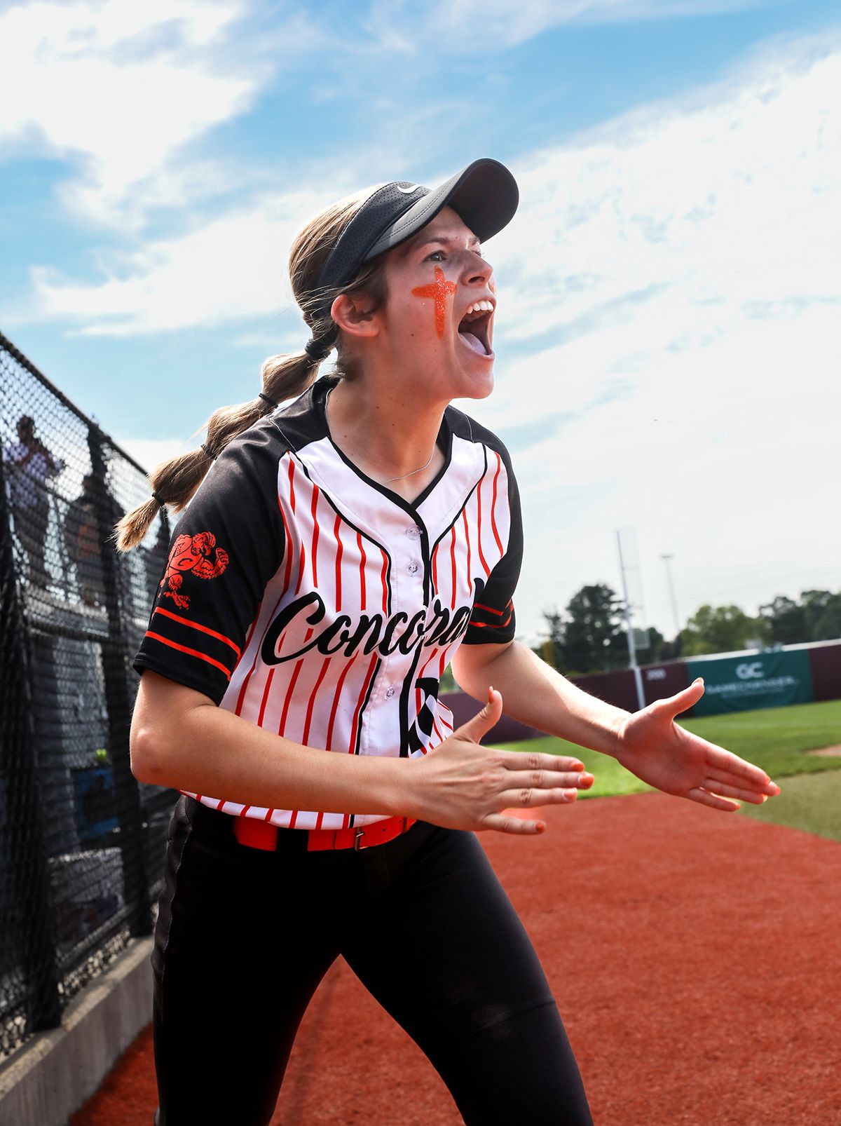 Softball players in striped uniforms showing excited reactions during game.
