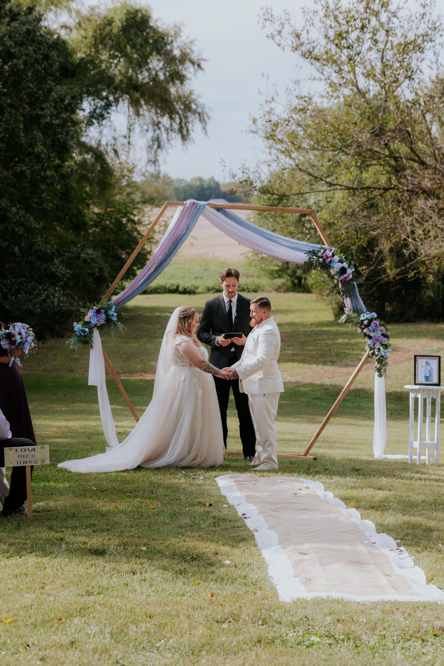 Outdoor wedding ceremony setup with white aisle runner and purple decorations in St. Louis.